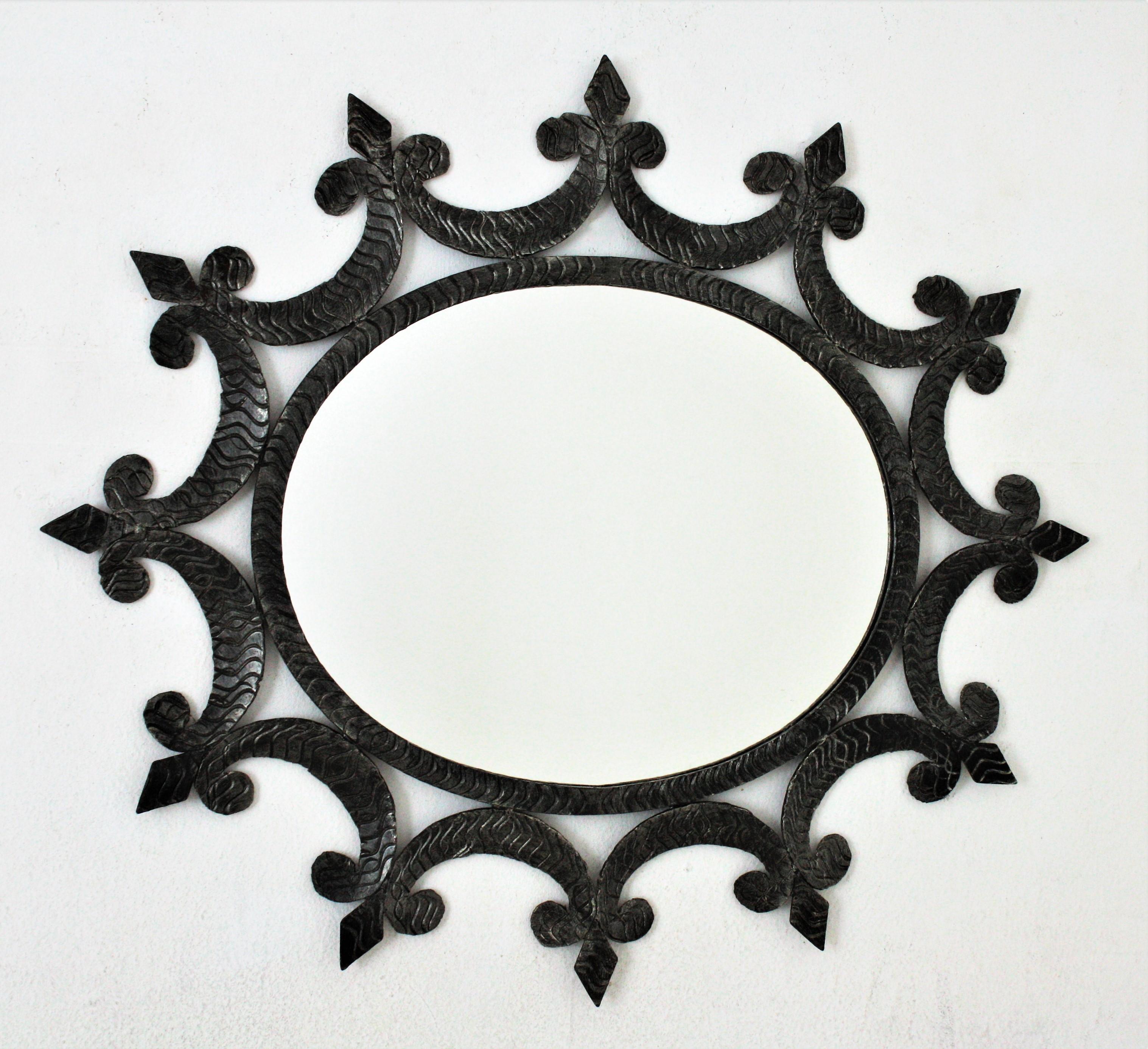 Wrought Iron Oval Sunburst Mirror with Scroll Details and Brutalist Design, Spain, 1950-1960.
Eye-catching hand forged iron mirror with scroll decorations, fleur-de-lis accents and oval shape.
This beautiful oval mirror is heavily decorated by