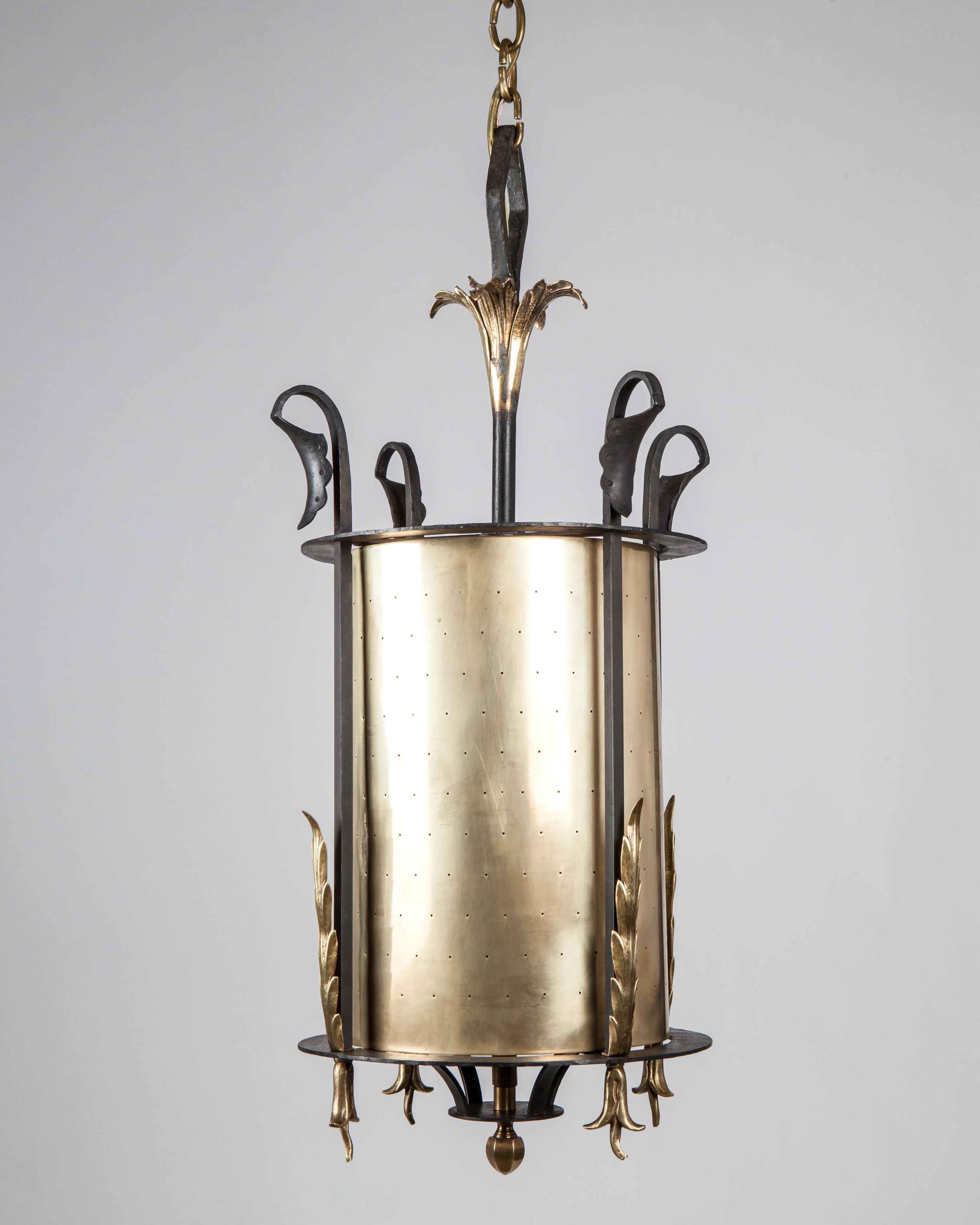 AHL4163
A round vintage pendant lantern with a blackened wrought iron frame holding a brass cylinder pierced overall with small pinpoint holes. The shade and foliate details all in a mellowed brass finish. Circa 1950s.

Dimensions:
Current