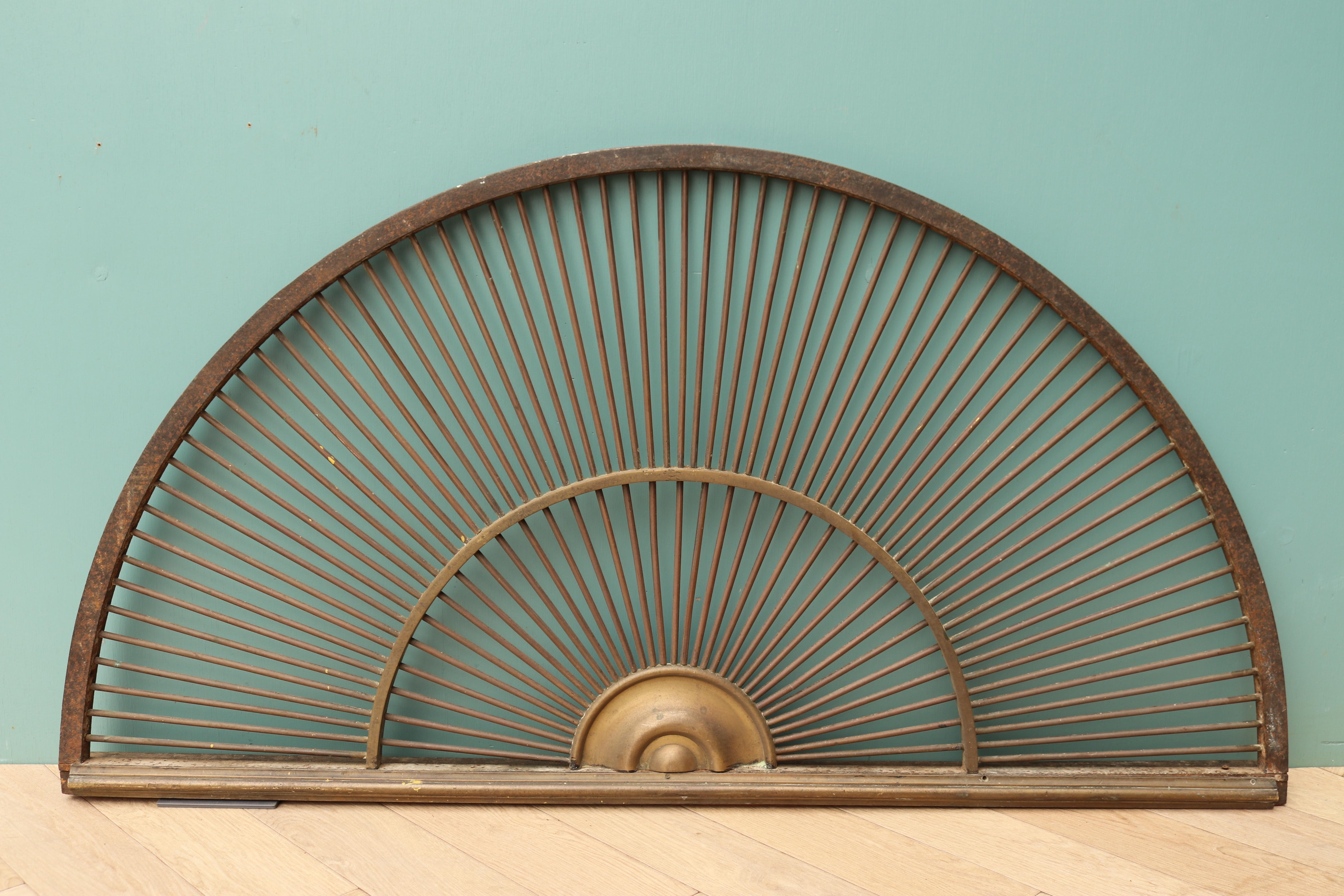A reclaimed wrought iron fan light with a brass roundel, finished to resemble bronze.