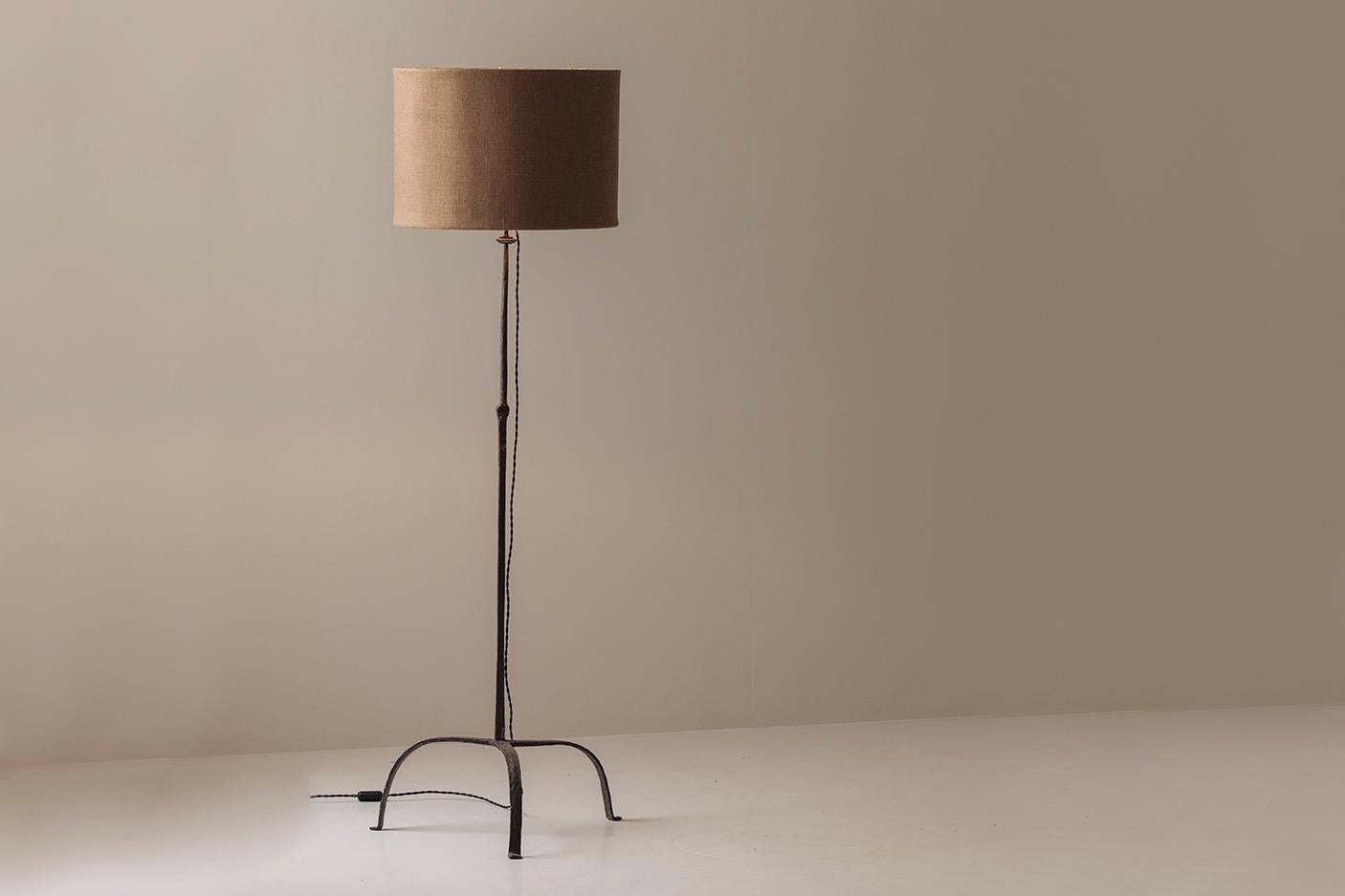 Elegante nella sua semplicità e ricca di carattere, questa lampada da terra rustica risale agli anni '30 ed è un esempio lampante dell'artigianato francese dell'inizio del XX secolo. Realizzato in ferro battuto forgiato a mano, il gambo sottile si