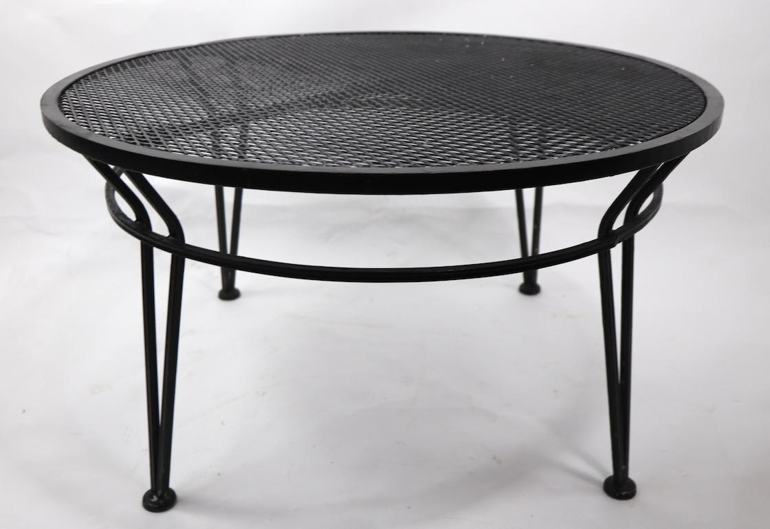 Wrought iron patio, garden coffee, or cocktail table by Salterini. Originally designed for outdoor, but also suitable for indoor use. Wrought iron structure and legs, metal mesh top. Currently in later, but not original, black paint finish. We offer