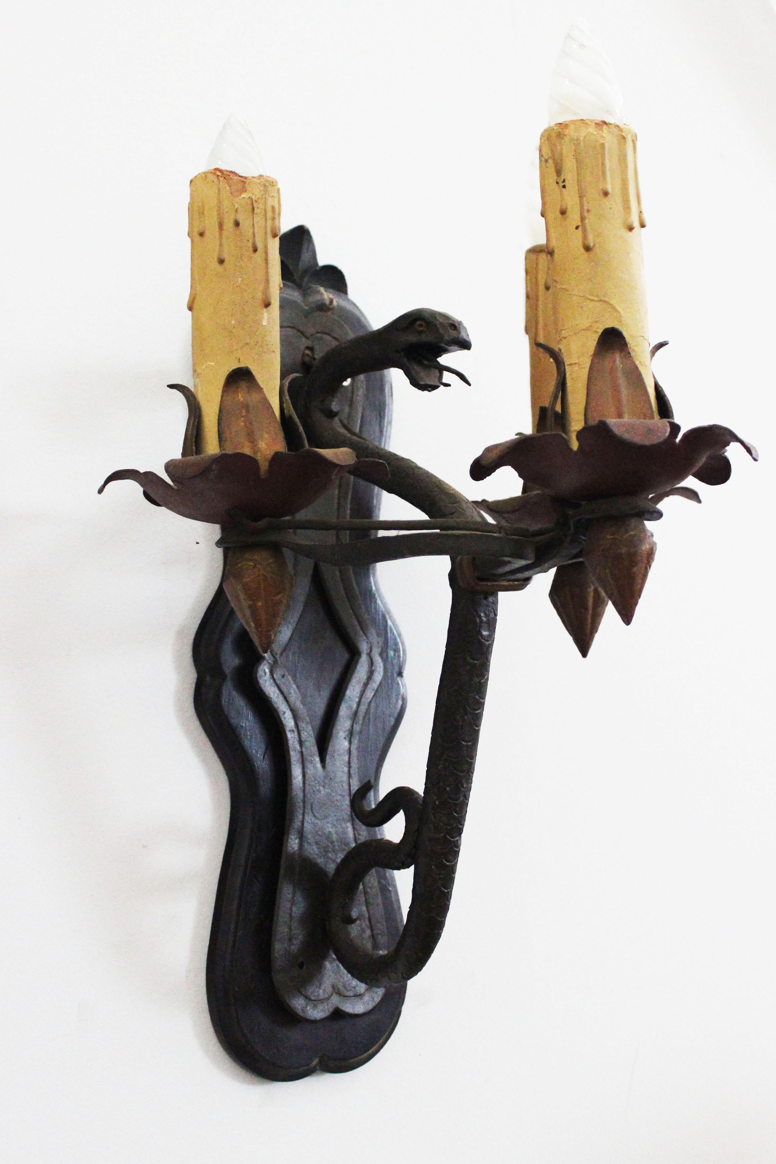 Pair of wrought iron wall sconces, on a walnut wood base, the lamp holder in plastic.