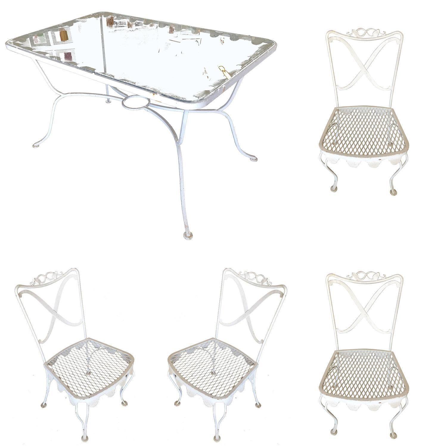 Woodard wrought iron scrolling pattern patio/outdoor set featuring four side chairs, two armchairs, and one glass-top dining table. The set is fashioned after the outdoor seating sets made popular on the streets of pairs combined with the wrought