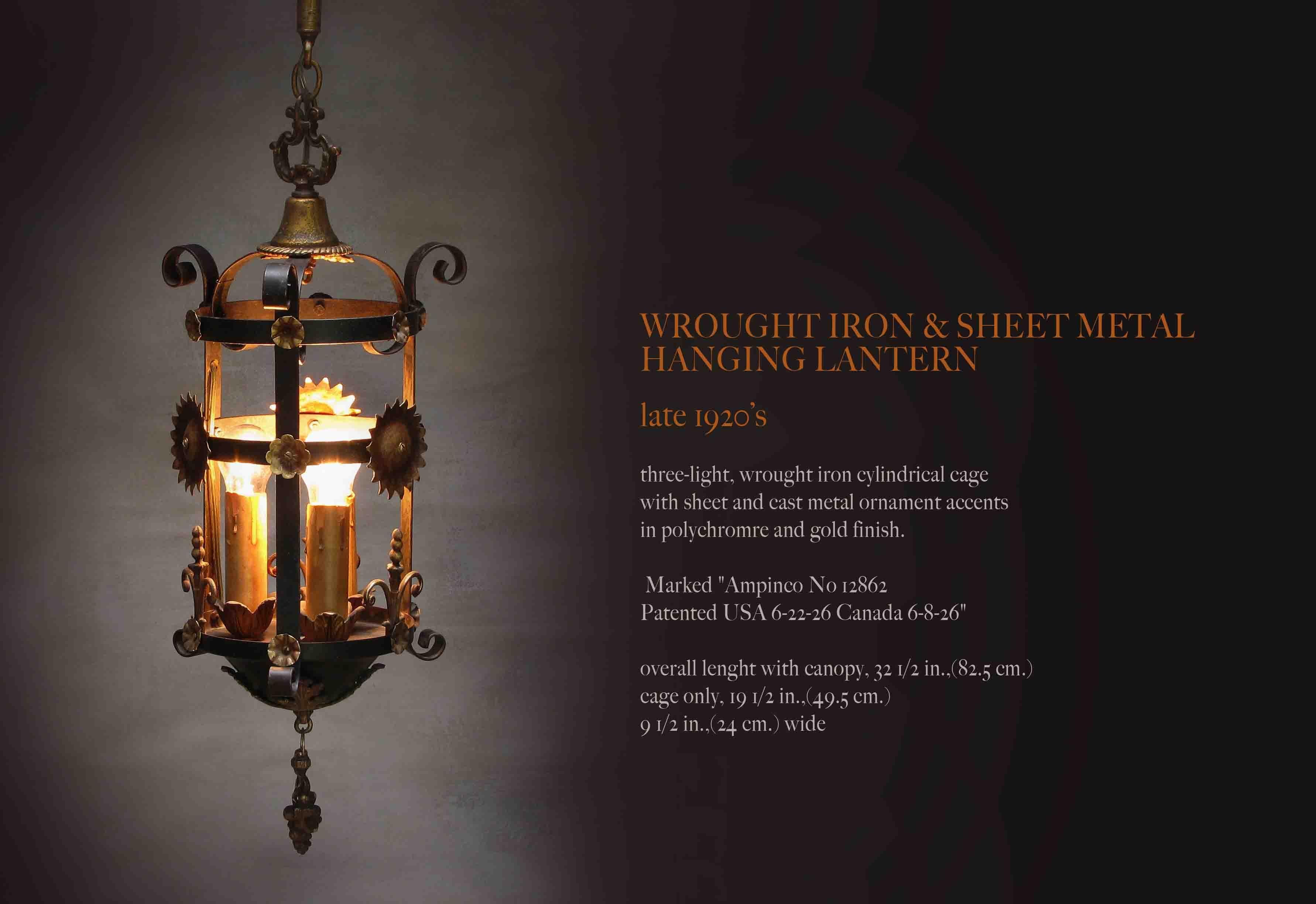 Wrought iron & sheet metal hanging lantern, circa Late 1920's
Three-light wrought iron cylindrical cage with sheet metal and cast metal ornamental accents in polychrome and gold finish.

Marked 