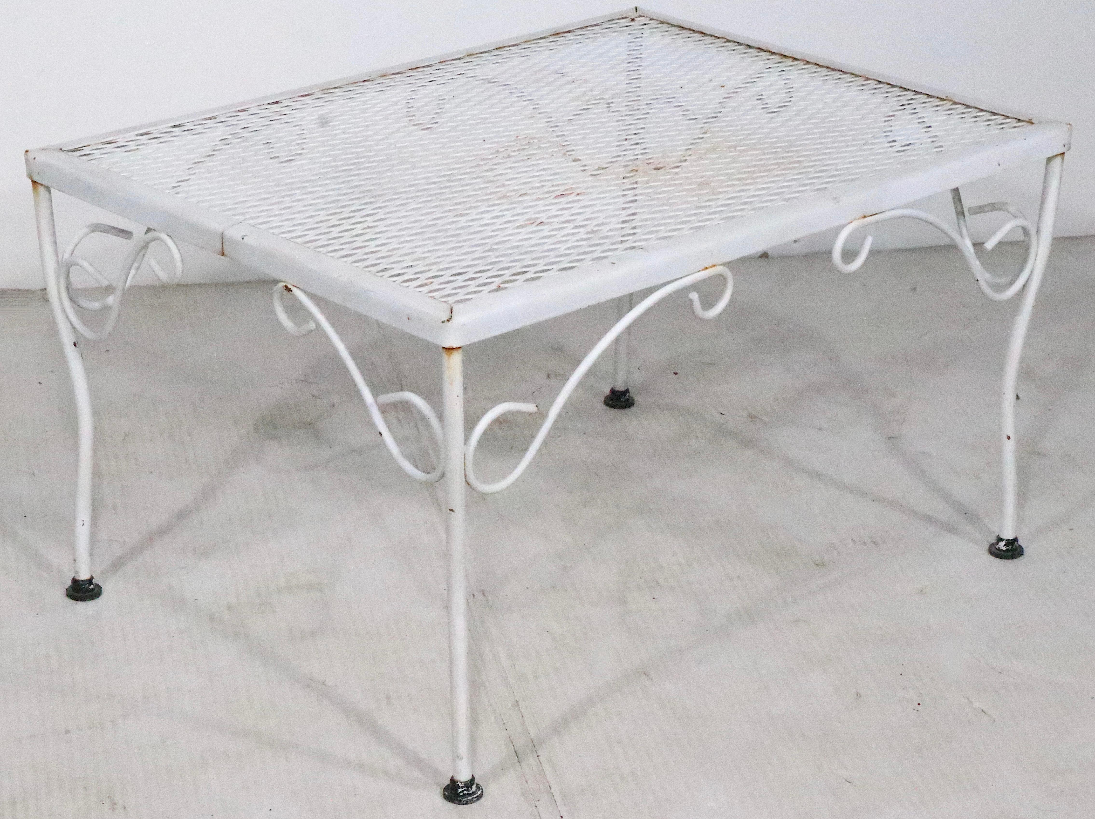 Side, or End table suitable for garden, patio, poolside, or sunroom, indoor and outdoor use. The table features a wrought iron base, and metal mesh top. This example is in very good, clean, original, ready to use condition, attributed to Woodard.
