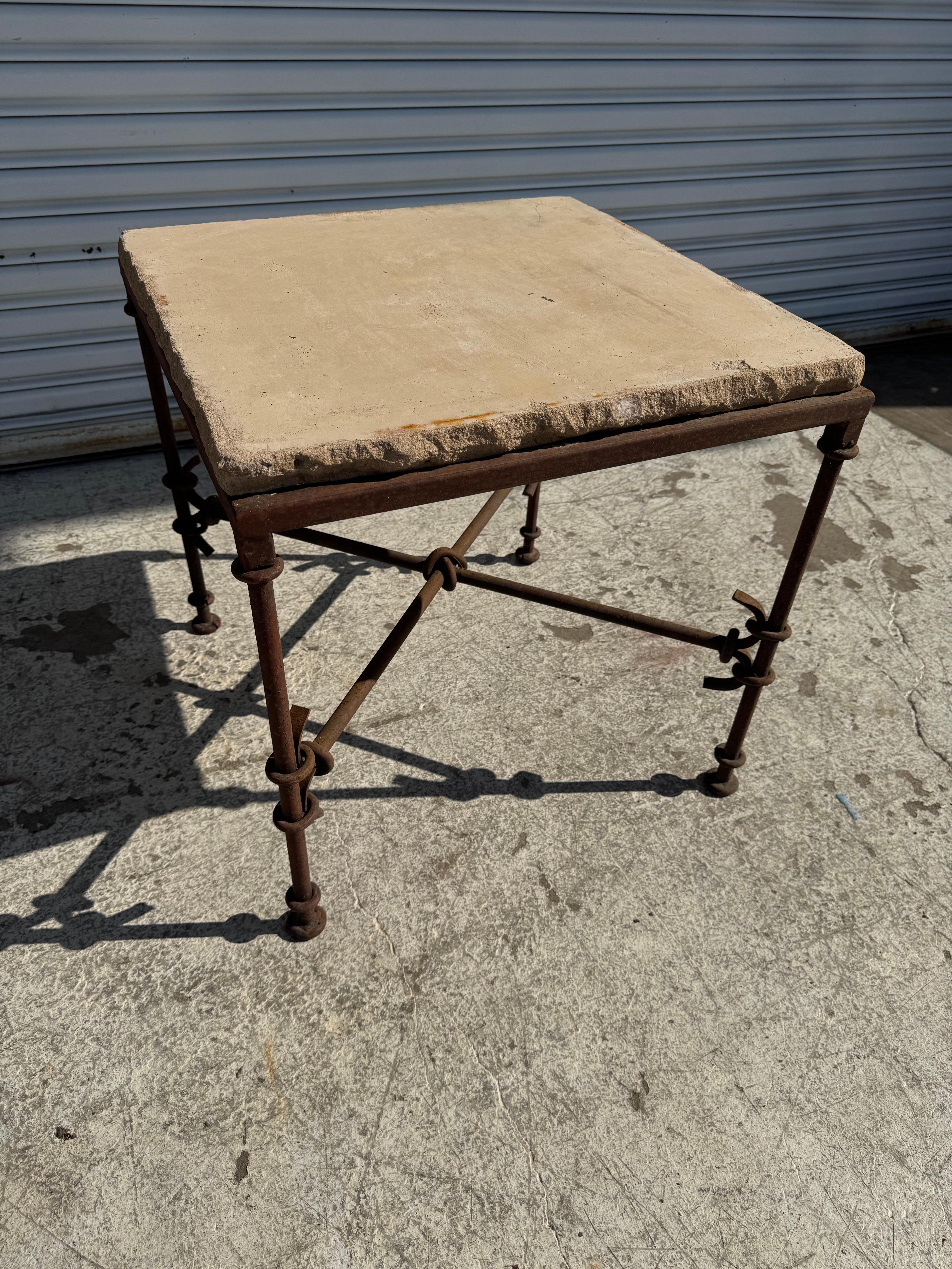 This wrought iron base table sculptured legs and a x-base stretchers.
The top is cut stone.