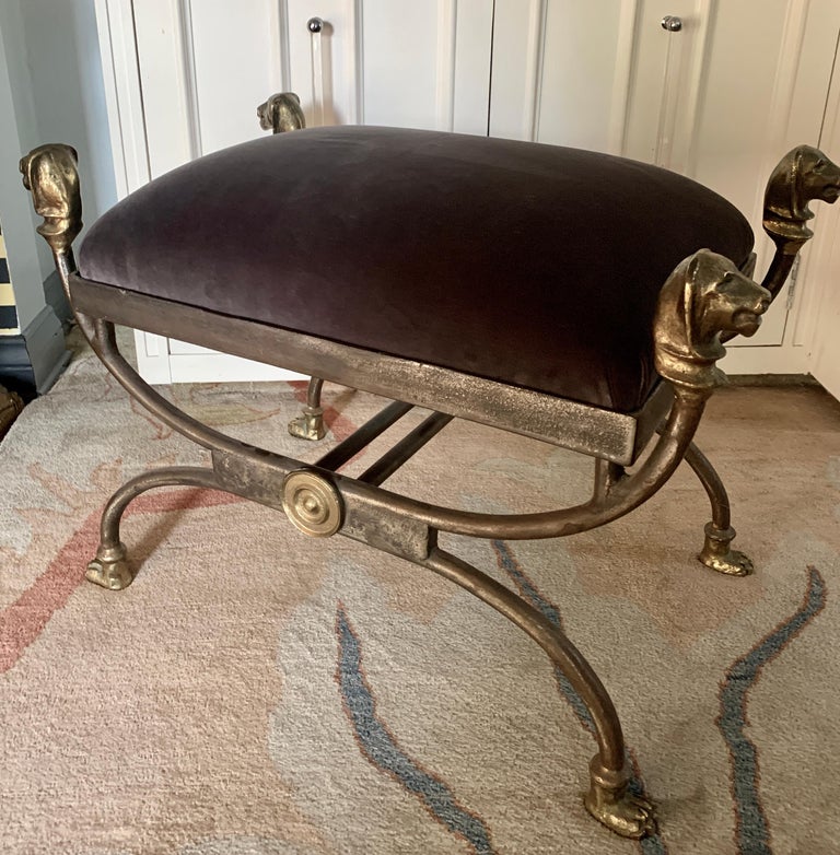 A wrought iron stool with cast brass head finials and paw feet and medallion. The shape and detailing are exceptional. A fabulous statement in newly upholstered Belgian Velvet. A compliment to any room, foot of the bed to library and guest