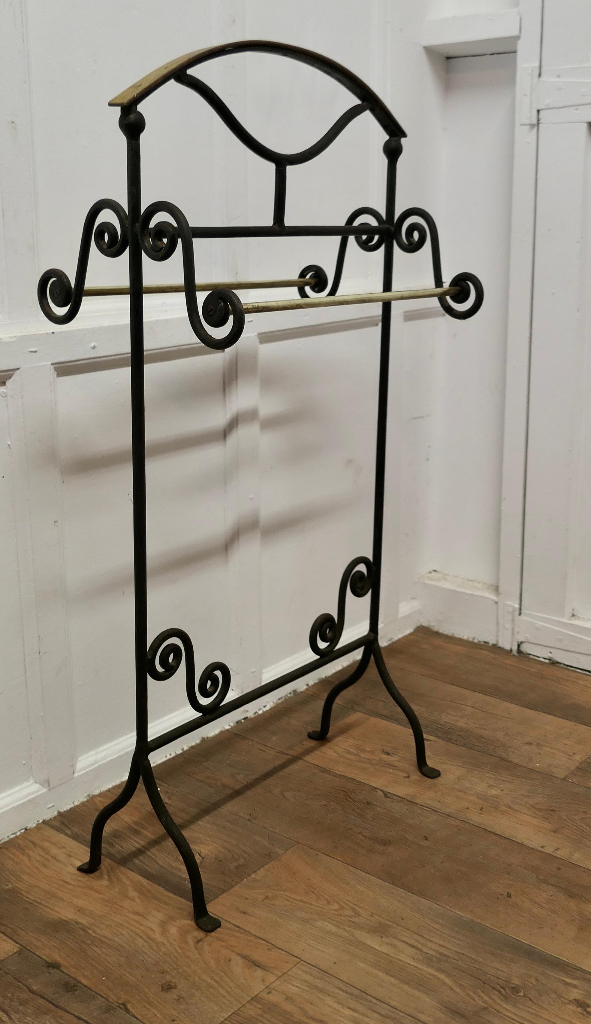 Wrought Iron Towel Rail or Clothes Airer

The Towel Rail or Clothes Airer has pretty scroll shaped sides, with an arched beech top rail it has brass hanging rails on either side,  the towel rail is painted in black. 
All in good condition and very