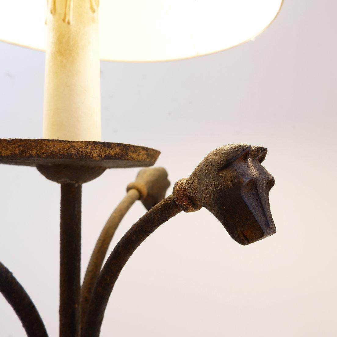 Dreibeinige Stehlampe aus Schmiedeeisen, verziert mit stilisierten Tierköpfen
Brutalistisch - Primitiv - Stehleuchte
Maße: Ø 67cm H:167cm 
Obere Lampenfassung ist zu überprüfen
Stehleuchte wird mit Lampenschirm verkauft