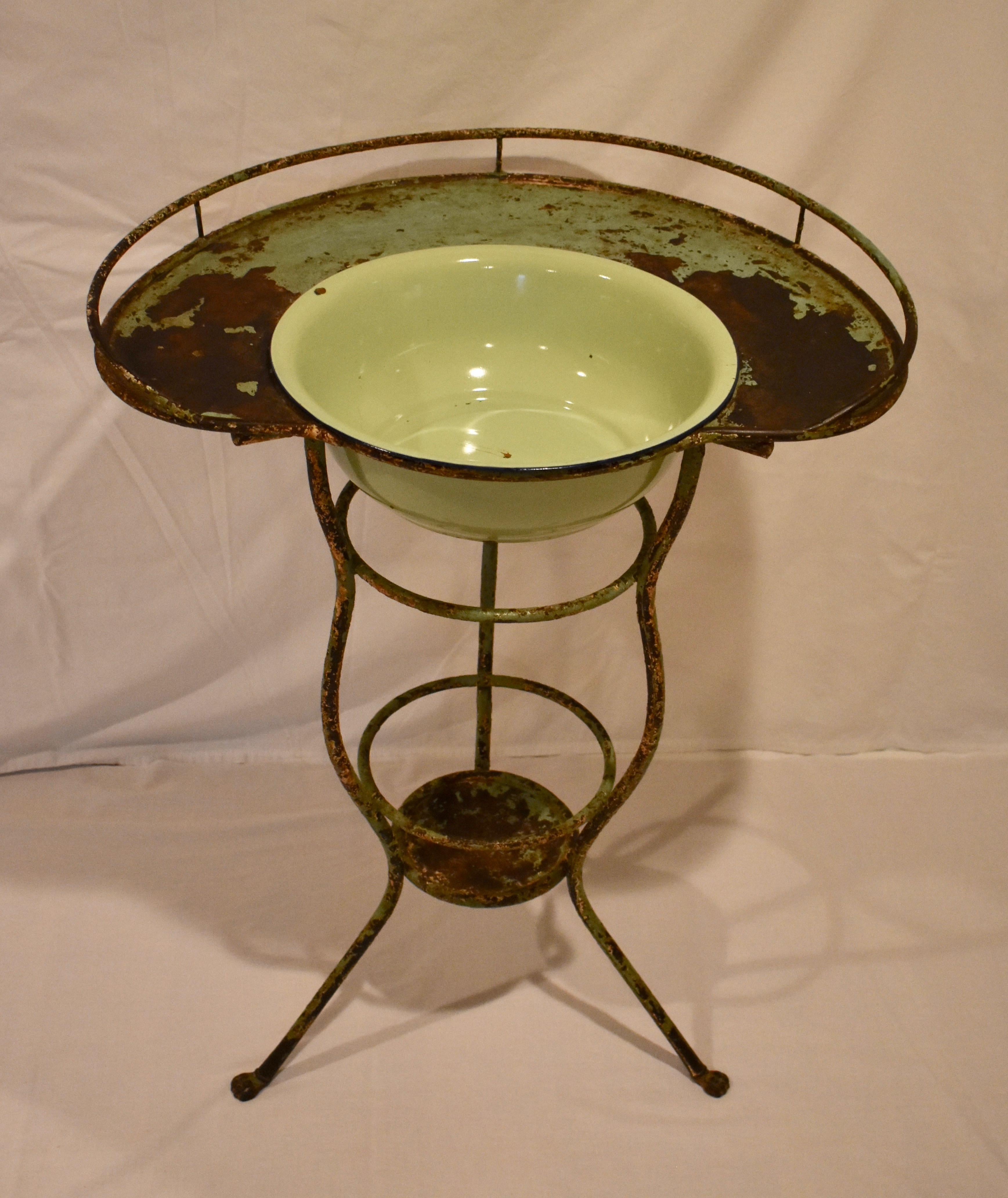 This beautiful and rather unusual French curvilinear wrought iron washstand features a kidney-shaped surface with a beaded lip and gallery. This is supported by three serpentine legs ending in paw feet, joined by two iron rings and a lipped shelf 7”