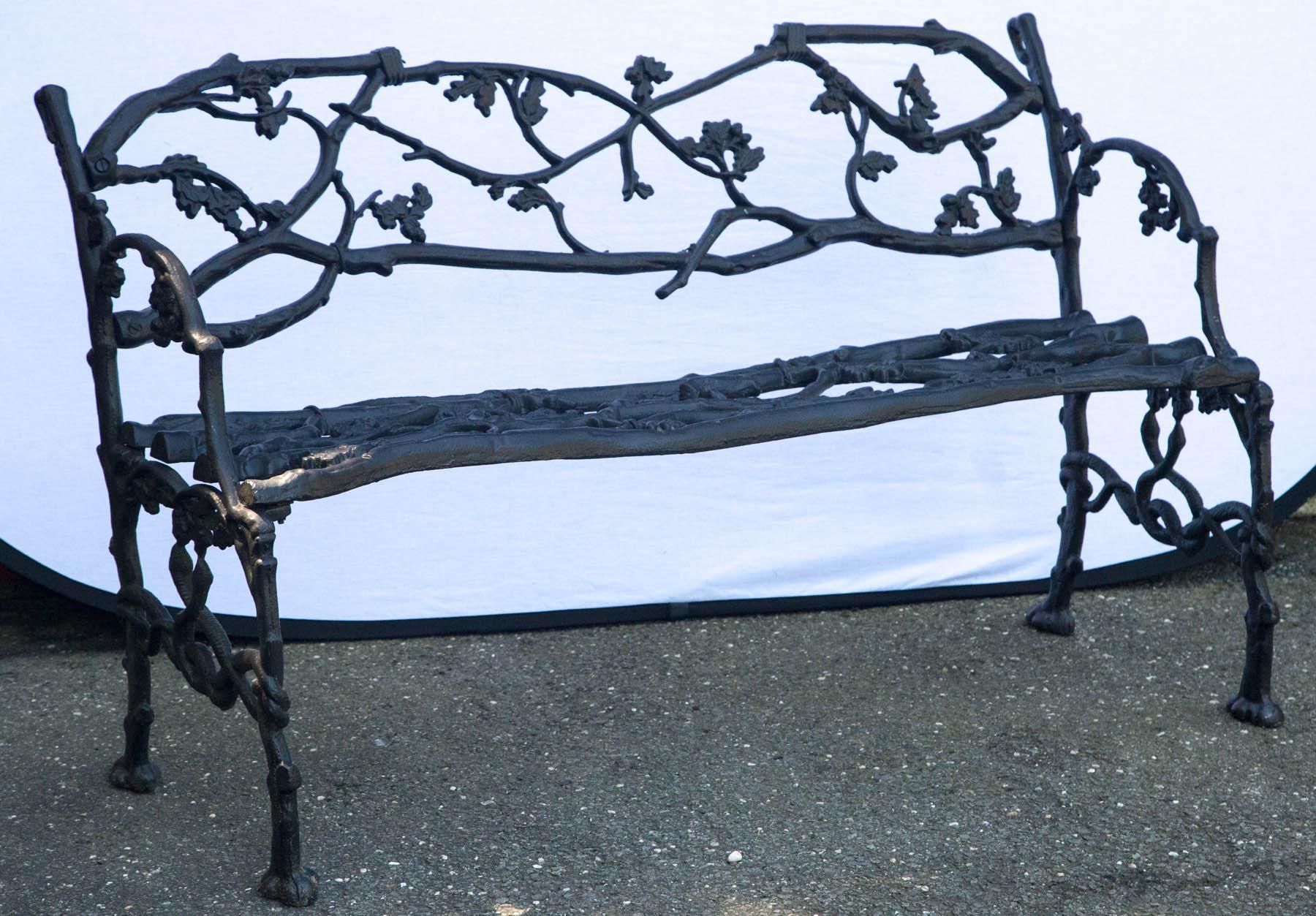 Wrought iron twig form bench having leaf decoration and intertwined snake stretcher.