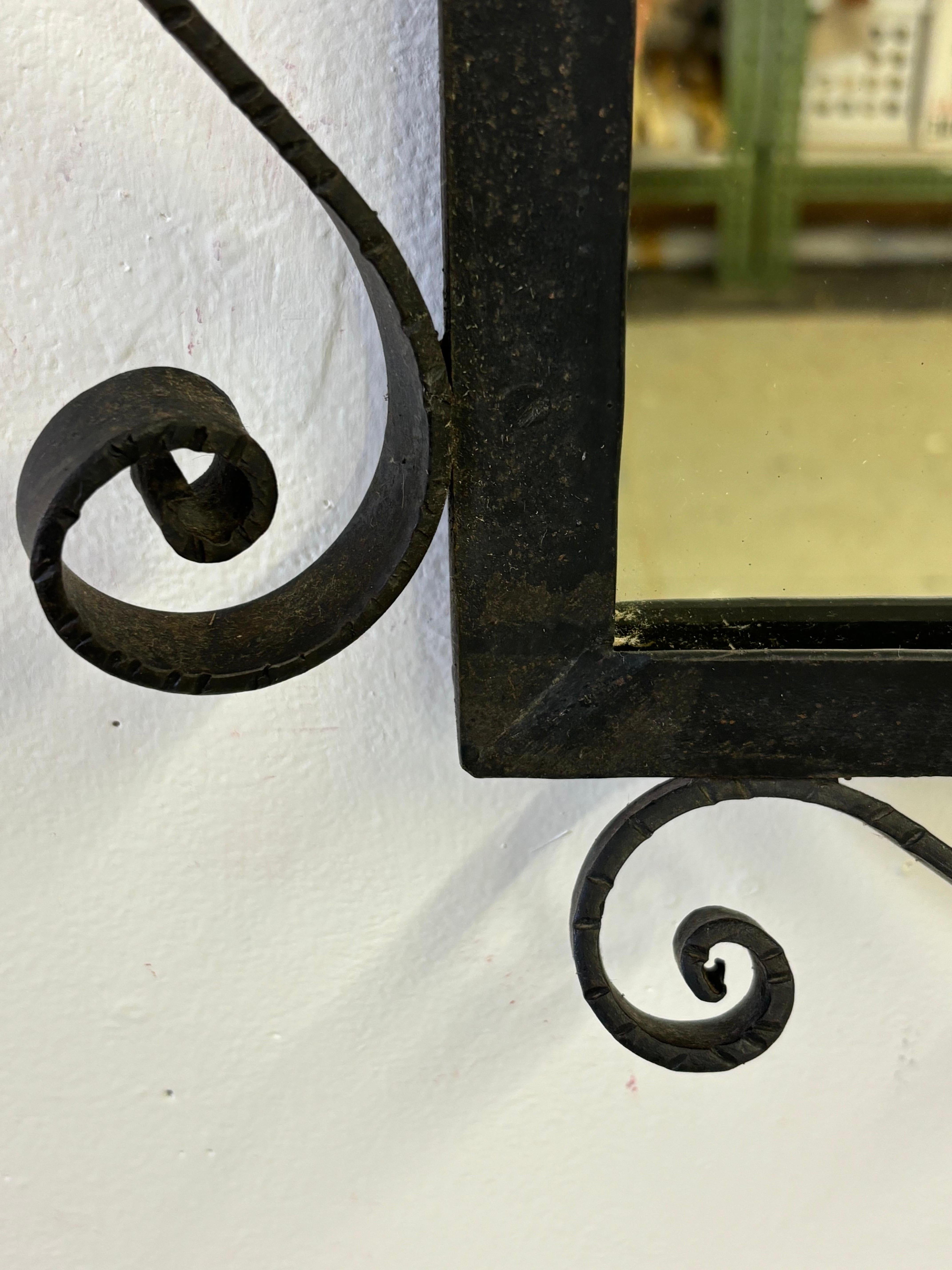 Miroir mural en fer forgé avec une belle attention portée à la ferronnerie.  Les ferronneries s'inclinent à environ 2,5 pouces du mur.  La taille réelle du miroir est de 17,75 x 13,5