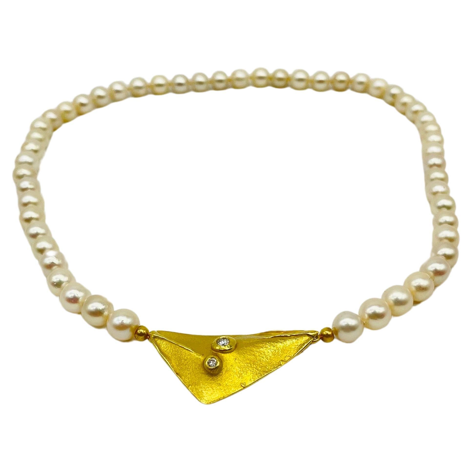 Plongez dans la beauté onirique de ce collier de perles exquis et élégant, arborant des perles d'une subtile teinte champagne. Les perles dégagent un charme intemporel et, en pendentif, ce collier présente une forme triangulaire gracieusement