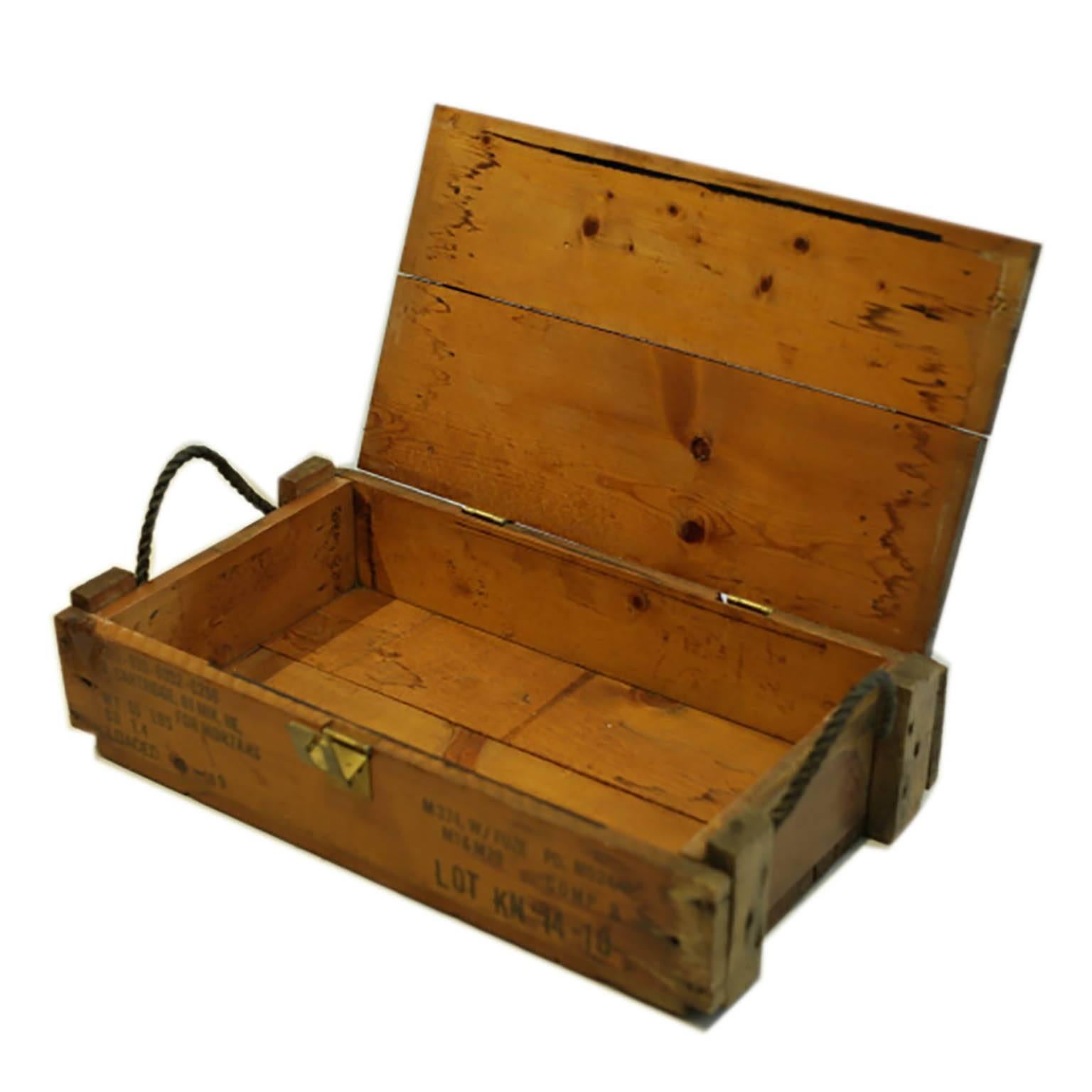 Wooden box with a hinged latch and rope handles used to carry mortar shells.
