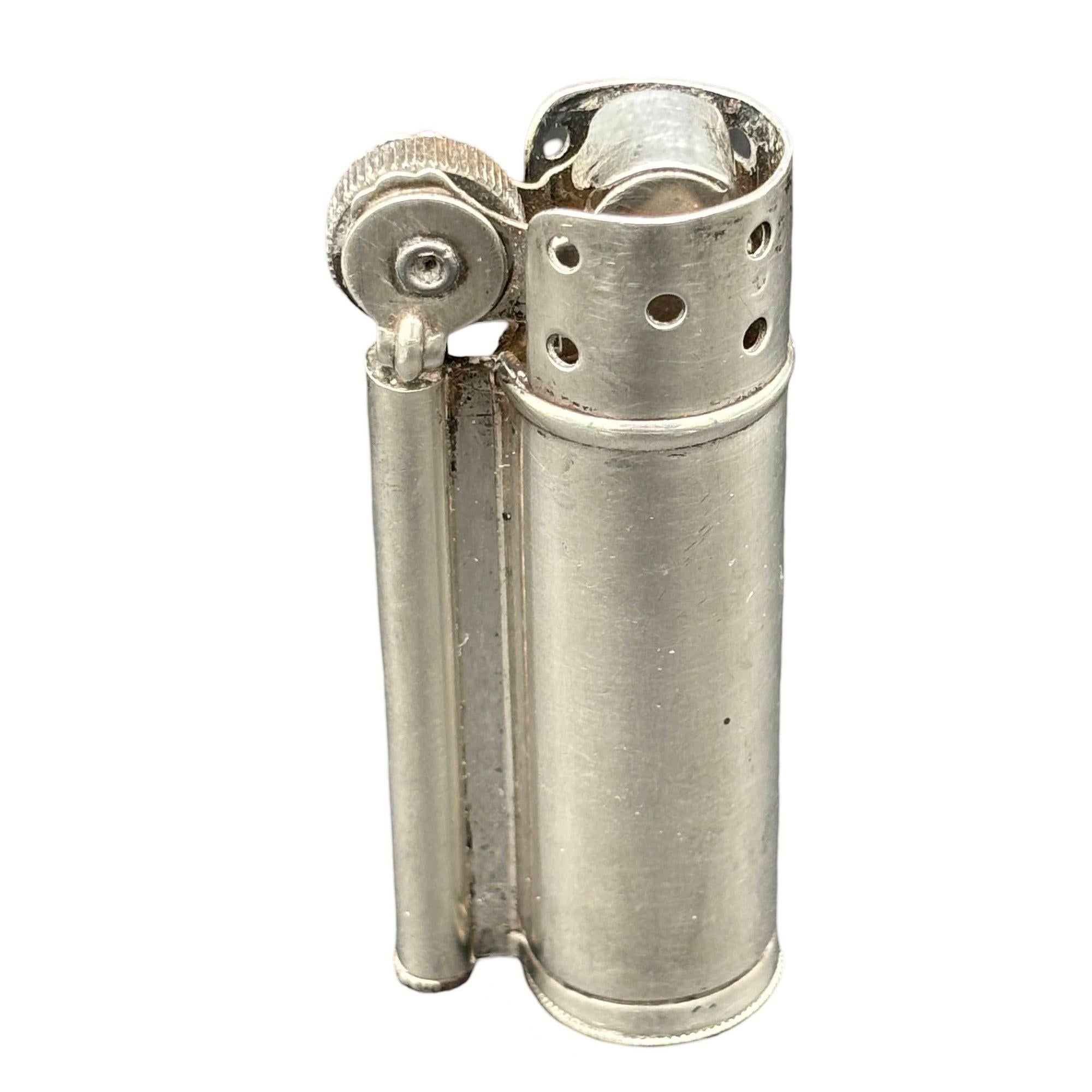 Questo accendino vintage Dunhill, realizzato in argento 925, risale all'epoca della Seconda Guerra Mondiale ed è stato prodotto negli Stati Uniti. Conosciuto come accendino da trincea o accendino militare, è dotato dell'iconico meccanismo di