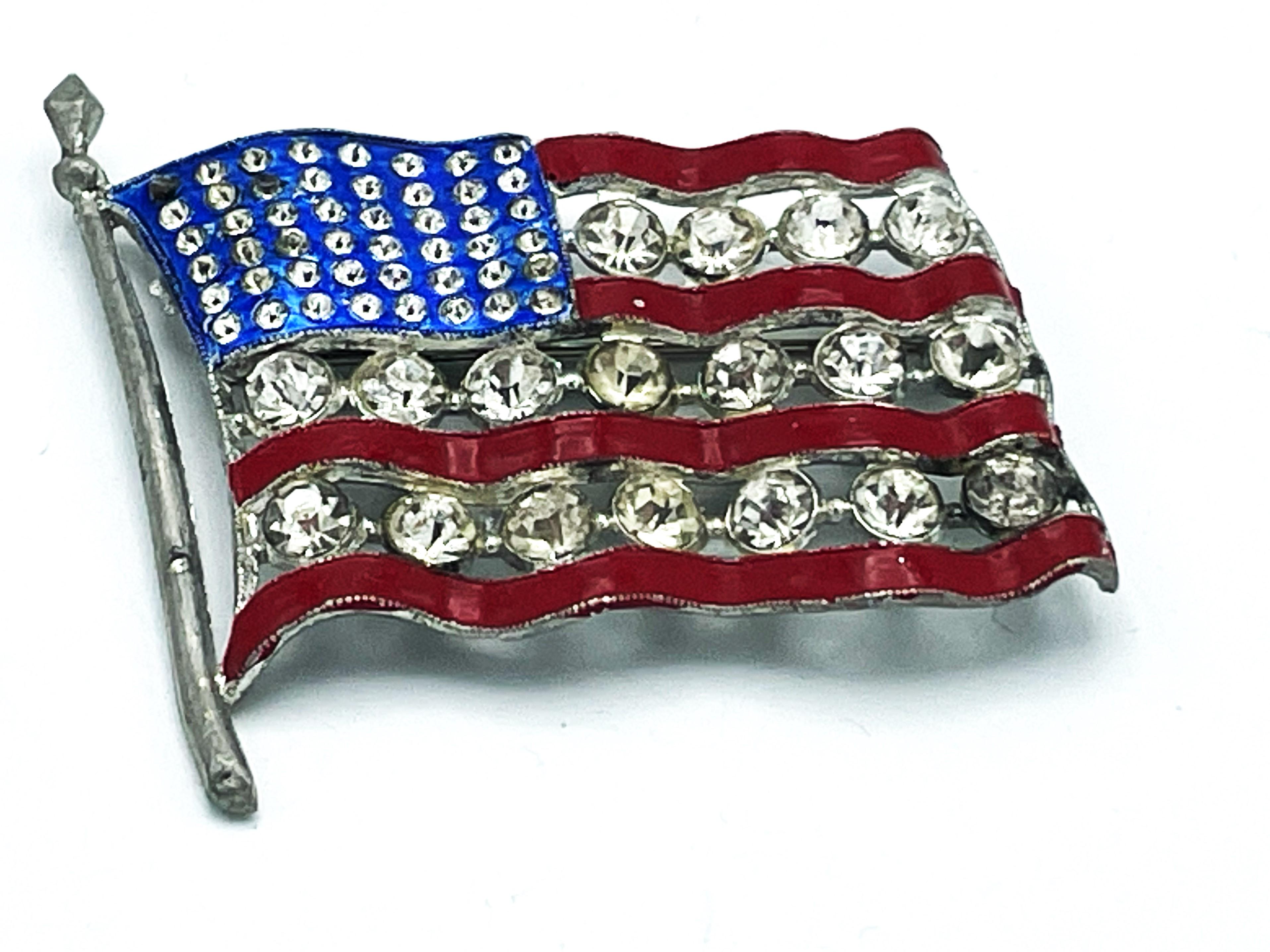Vintage WW2 US patriotic flag, red and blue enamel, large rhinestones. All rhinestones individually set and cut. Material Potash.

Dimensions:
Height 4 cm x 5,5 cm, flagpole 5,5 cm 
Very good condition.