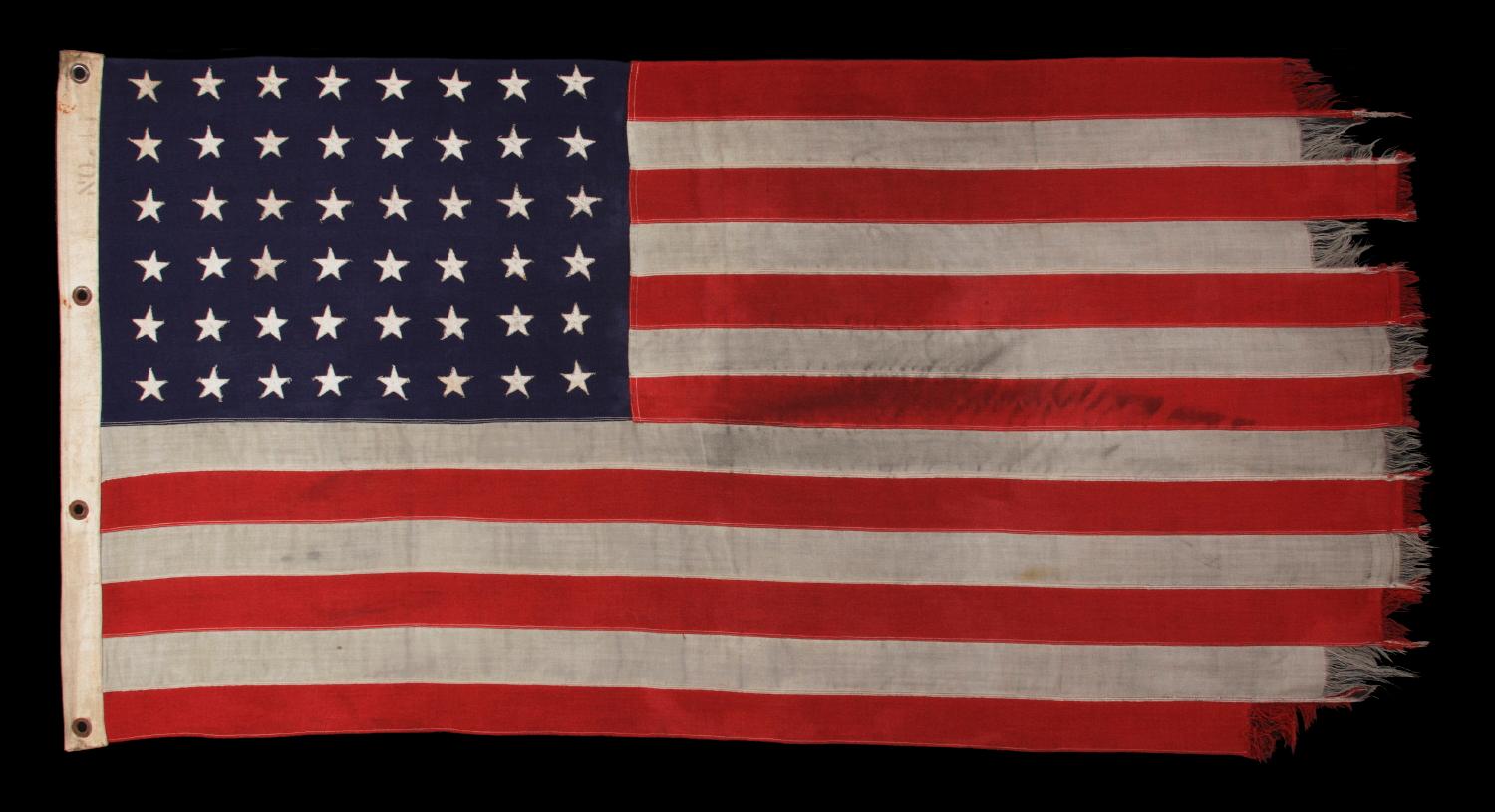 WWII VINTAGE ANTIQUE AMERICAN FLAG WITH 48 STARS AND ENDEARING WEAR FROM OBVIOUS LONG-TERM USE, A U.S. NAVY SMALL BOAT ENSIGN MARKED 