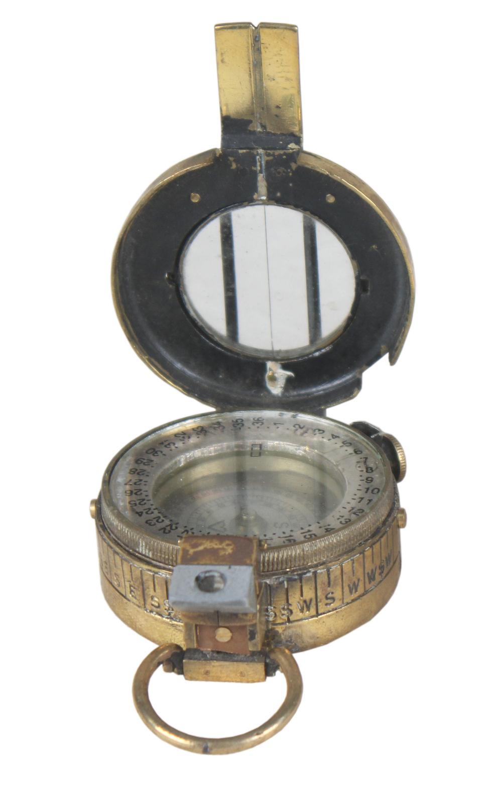 A working brass pocket compass marked London, 1942 on the back. Nickel dial. With hinged glass magnifier. WWII English. TG Co. Ltd.