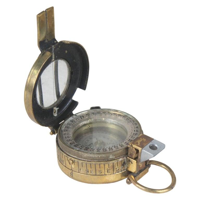 A brass World War II pocket compass marked London, 1944 on the back. Nickel rim with mother of pearl dial in working order. A hinged glass magnifier and when flipped over and brought to the eye and lined up at a 90 degree angle with the indicator