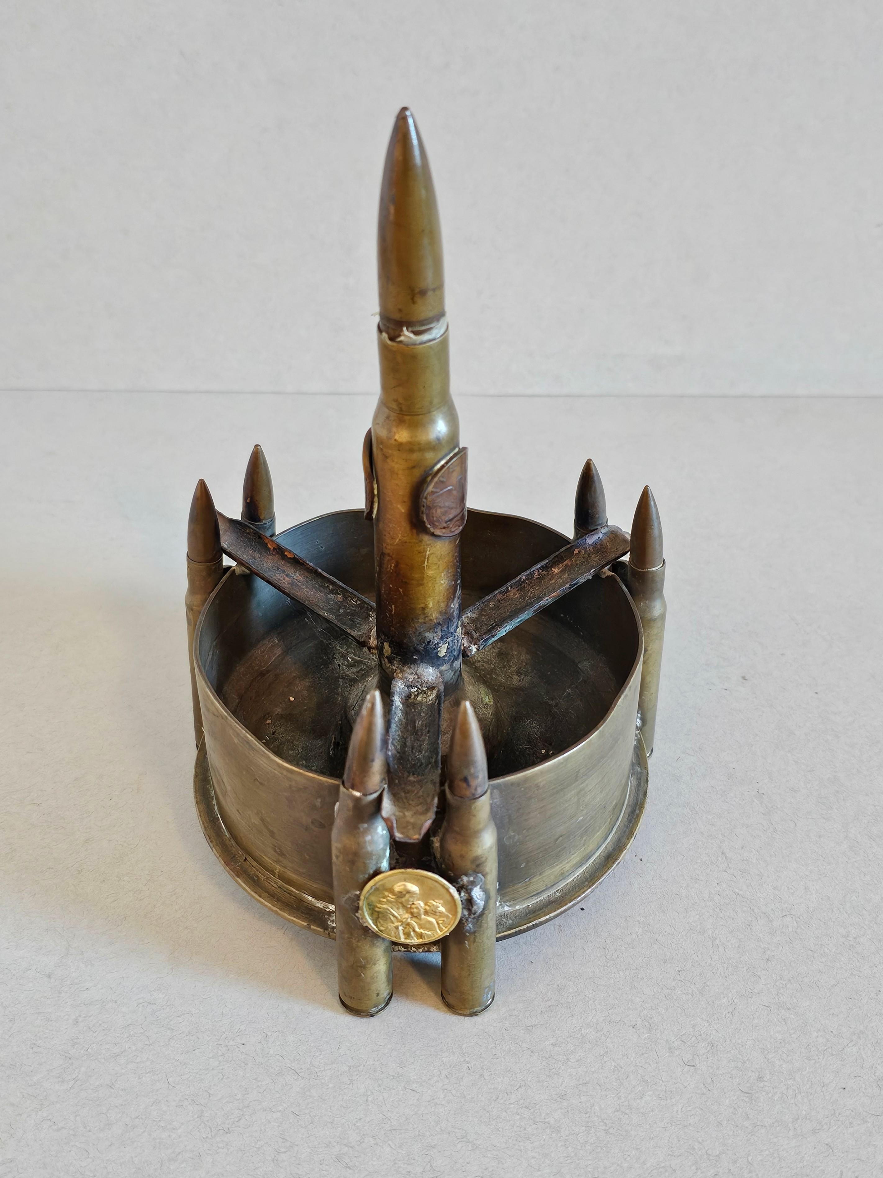 A fascinating Word War II trench art sculptural ammo ashtray.

Typically hand-crafted by a soldier from found objects during their down time at war, especially in the trenches of WW1, hence the name, this interesting munitions folk art work consists