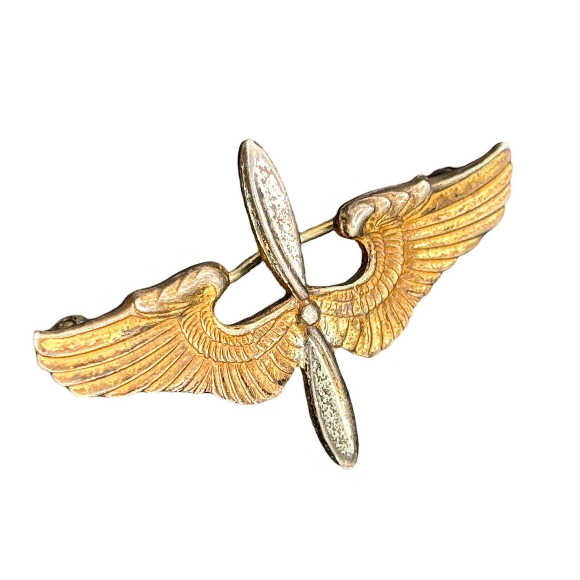 Original World War II U.S. Army Air Corps Aviation Cadet cap insignia, manufactured by Meyer of New York. Crafted in two parts, it features gold-plated wings and a silver-plated two-blade propeller, symbolizing a cadet’s status in training. This