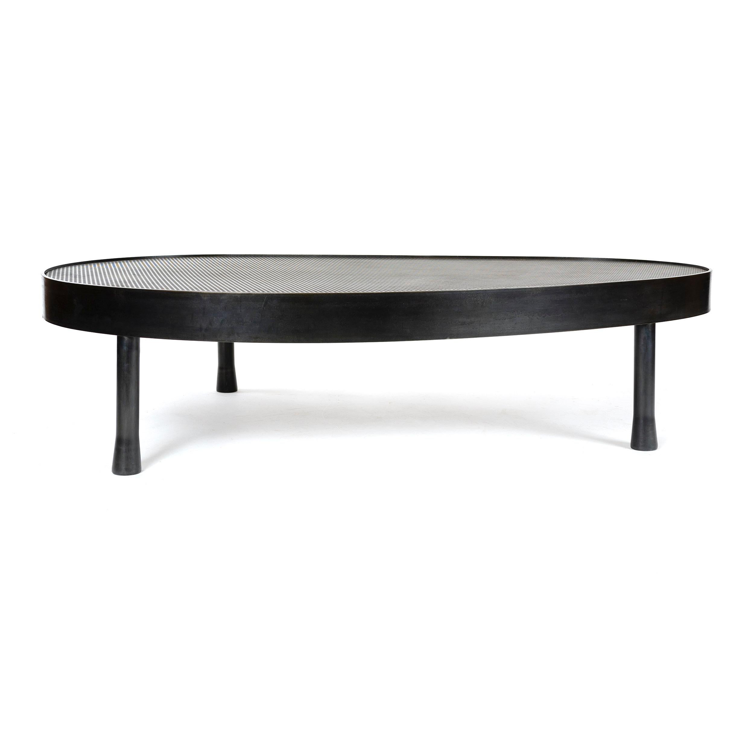 A low perforated steel coffee / cocktail table, supported by a heavy gauge steel band in an ovoid biomorphic shape on three flared tubular legs. 

Available in steel, stainless steel and bronze with surface materials in perforated metals, solid