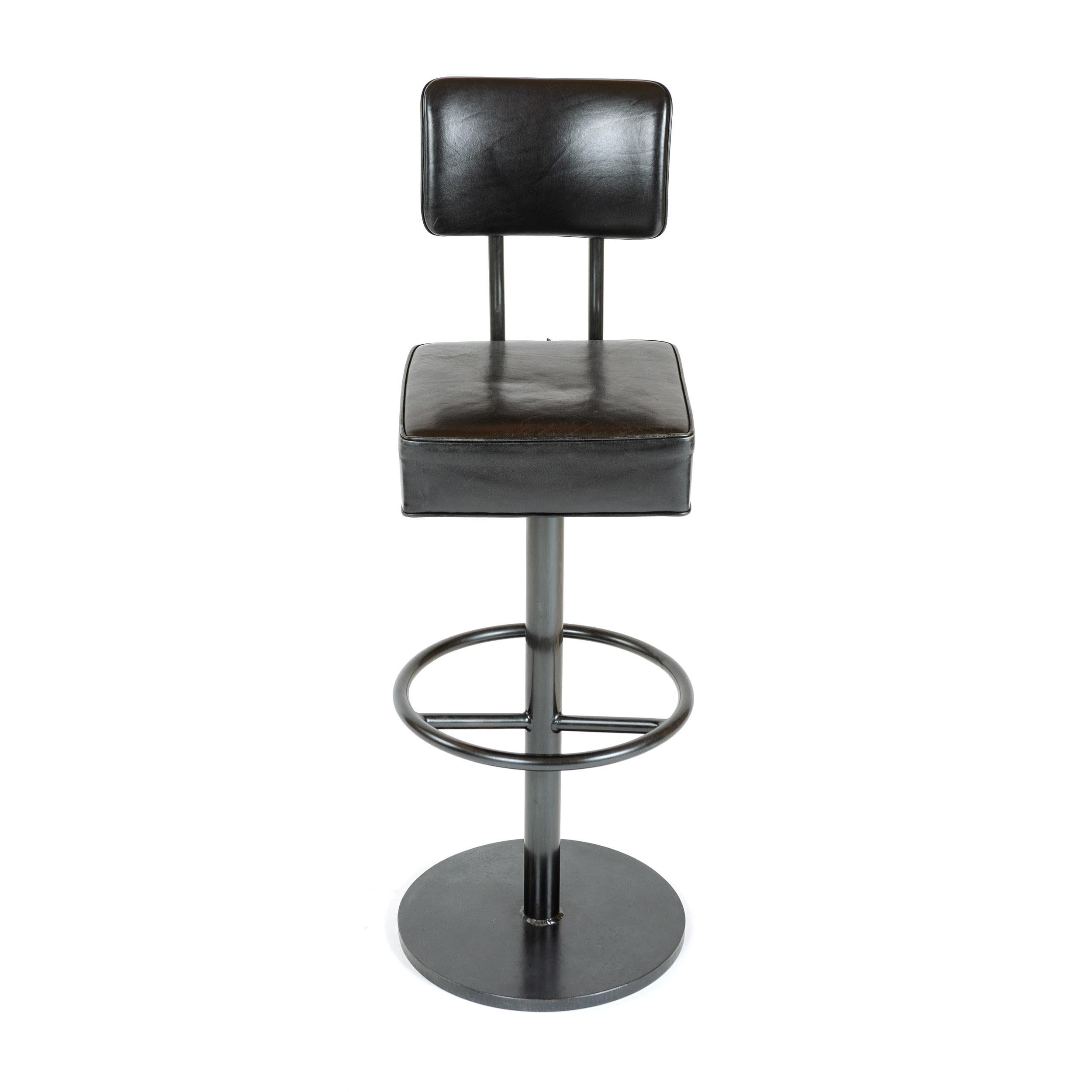 A custom height stool with upholstered seat and back on a patinated steel disc base.
          