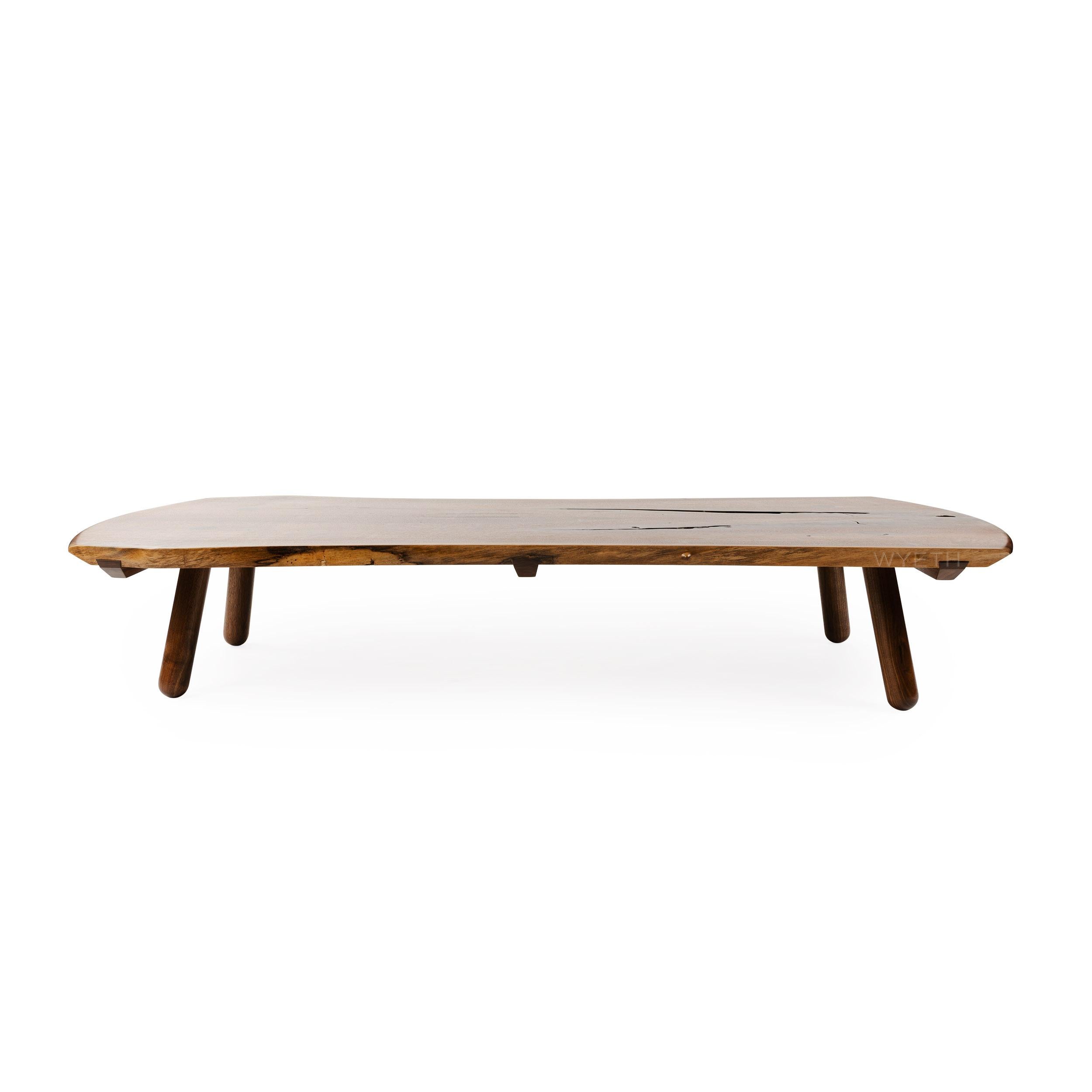 A unique handmade low coffee / cocktail table in bookmatched solid walnut with a rectangular form. The top consists of two (2) solid boards joined together with sliding dovetail stretchers and exposed natural edges. Four (4) substantial turned legs