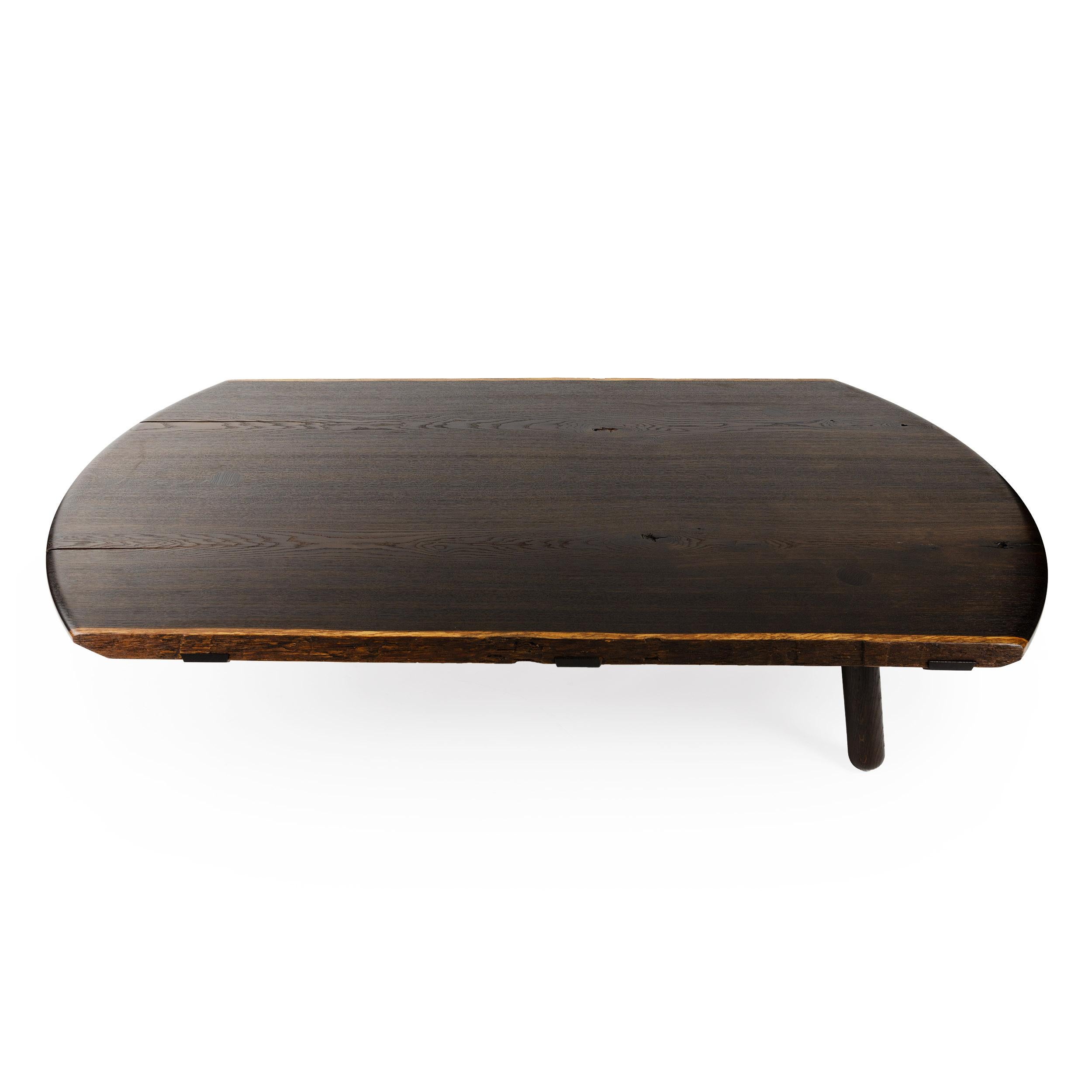 Al low cocktail / coffee table handcrafted in fumed oak with a rounded ends. Table features natural edges when innate in the wood and substantial turned legs that are mortised through the top. The top consists of live edges, and solid boards joined