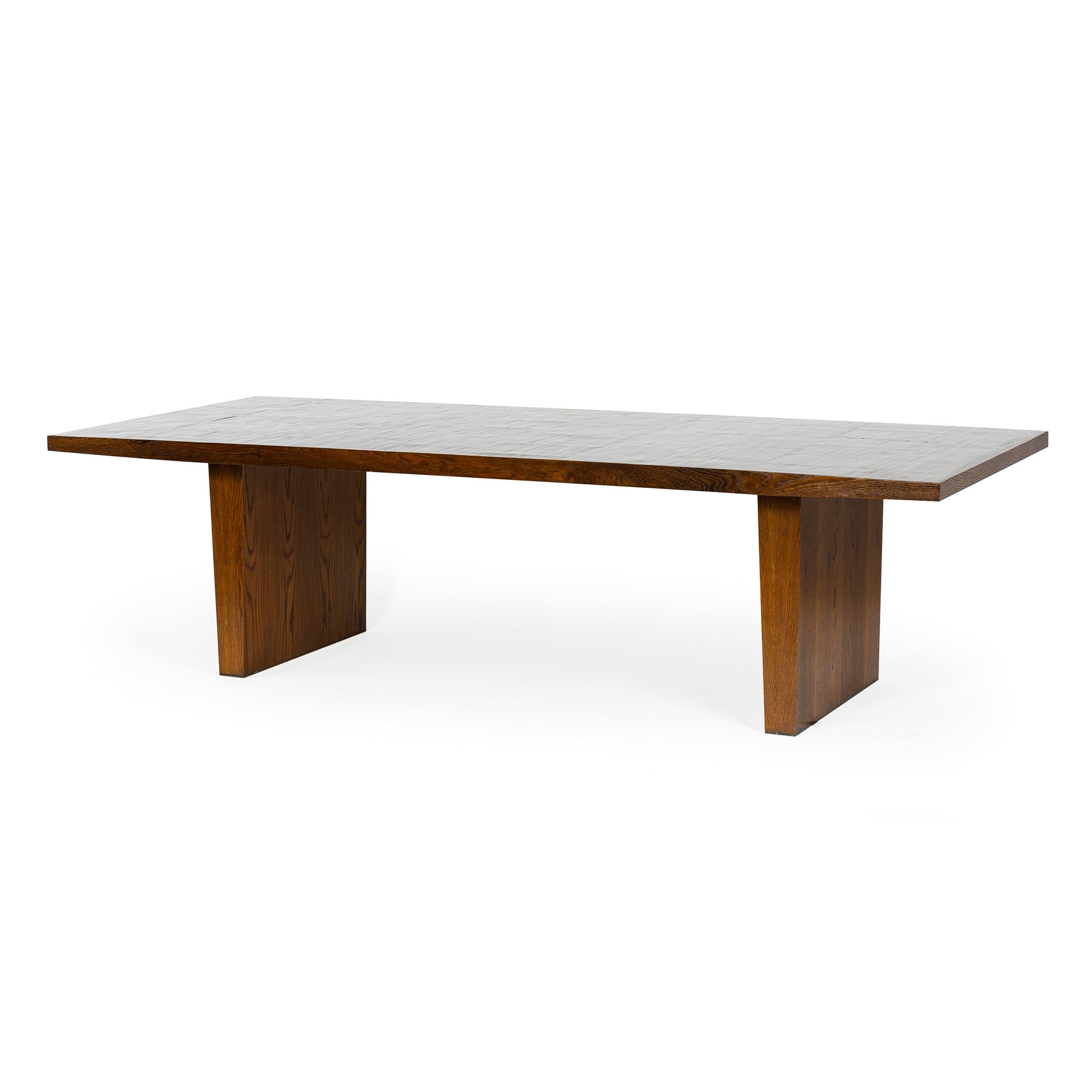 A dining table with a split bamboo top edged in oak with solid oak slab legs with brass feet, in a natural oil finish.