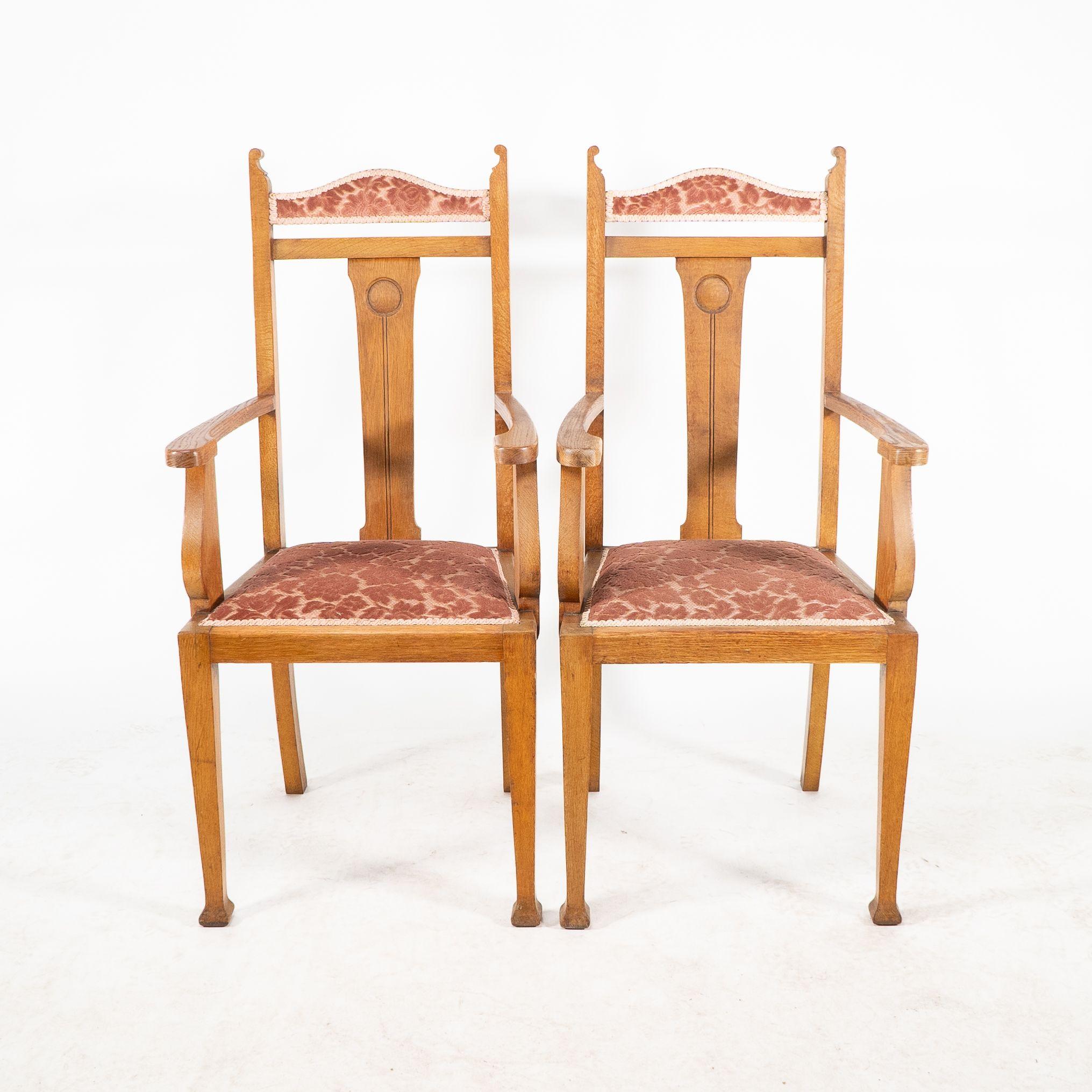 Wylie and Lochhead Glasgow. A set of six Arts and Crafts oak dining chairs with circular and line decoration to the back rest. Dimensions: Chairs H 105 cm x W 45 x D 42 cm; Armchairs H 114 cm x W 53.5 x D 50 cm Arm Height 74 cm Seat Height 47 cm