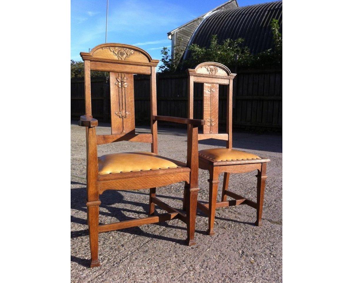 Wylie and Lochhead. A set of four Arts & Crafts oak dining chairs consisting of two side chairs and two armchairs, with stylized Glasgow rose and floral carved details to the backs, in good solid condition.
Professionally re upholstered in a quality
