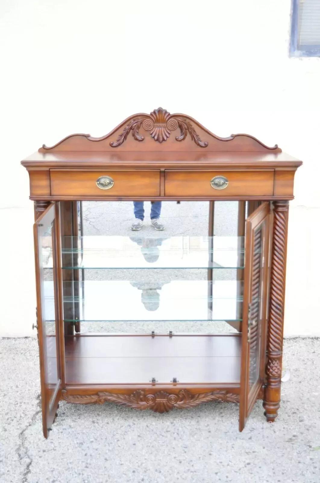 Empire Style Carved Cherry Wood Glass Display Curio China Cabinet by Wynwood Flex Steel. Item features a carved wood backsplash, spiral carved columns, original label, 2 drawers, 2 adjustable glass shelves, great style and form. Cabinet has a