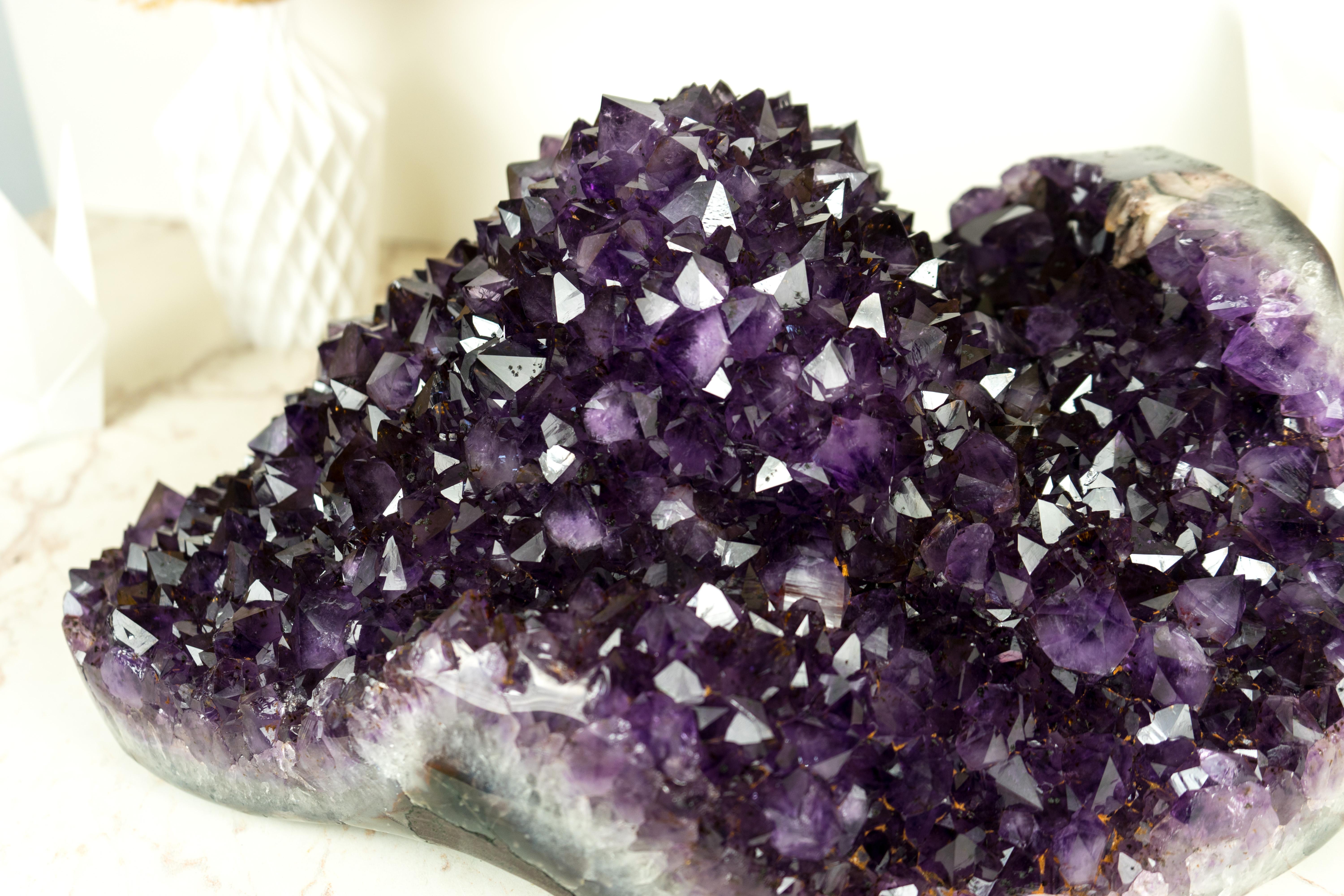 The Amethyst Flower Geode is not only a statement piece in your crystal collection but also a captivating centerpiece for your space decor. This specimen possesses rarely seen aesthetics that blend seamlessly with the perfection of its points and