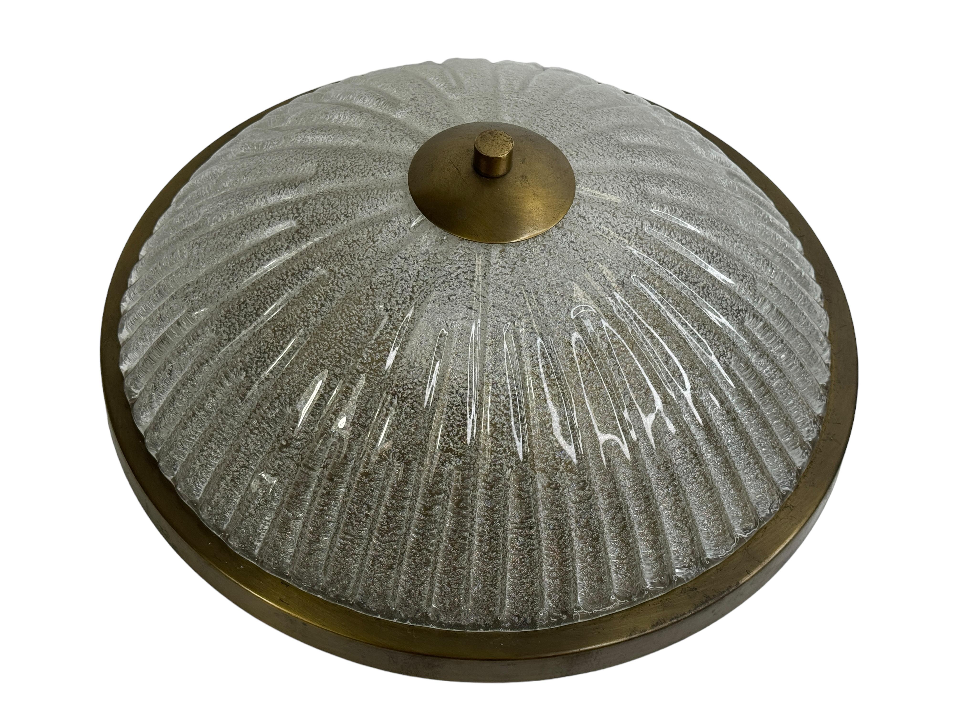 Un bellissimo incasso extra large del produttore tedesco Fischer Leuchten. Il grande elemento in vetro pesante è sostenuto da una piastra in ottone brunito con tre fonti luminose. Bellissimo vetro trasparente a onda su un apparecchio in metallo.