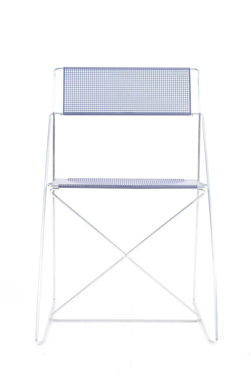 This stacking chair was designed in 1977 by Niels Jørgen Haugesen and produced by Hybodan A/S, Denmark. It features a chrome-plated steel frame, the original blue enameled perforated steel back and seat, and remains in a good vintage condition.
