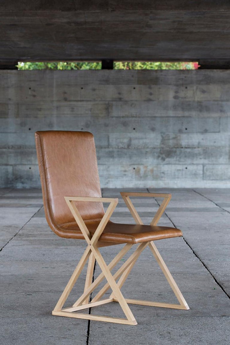 The X2 chair was launched at iSaloni 2015 in Milan. Its wooden frame shows two large X shapes on the sides, forming both the chair's feet and arms.