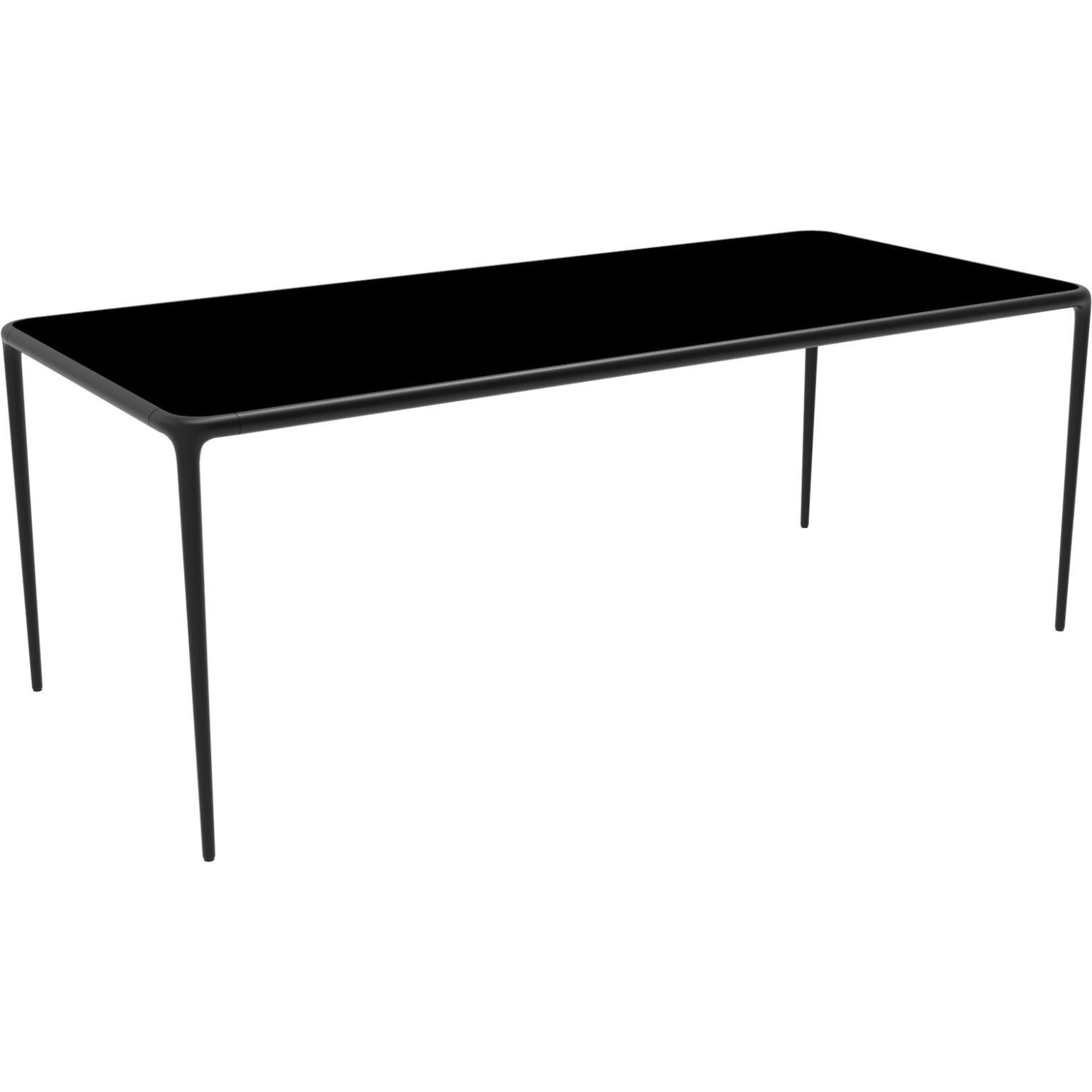 Xaloc black glass top 200 table by MOWEE
Dimensions: D200 x W90 x H74 cm
Material: Aluminum, tinted tempered glass top.
Also available in different aluminum colors and finishes (HPL Black Edge or Neolith). 

Xaloc synthesizes the lines of