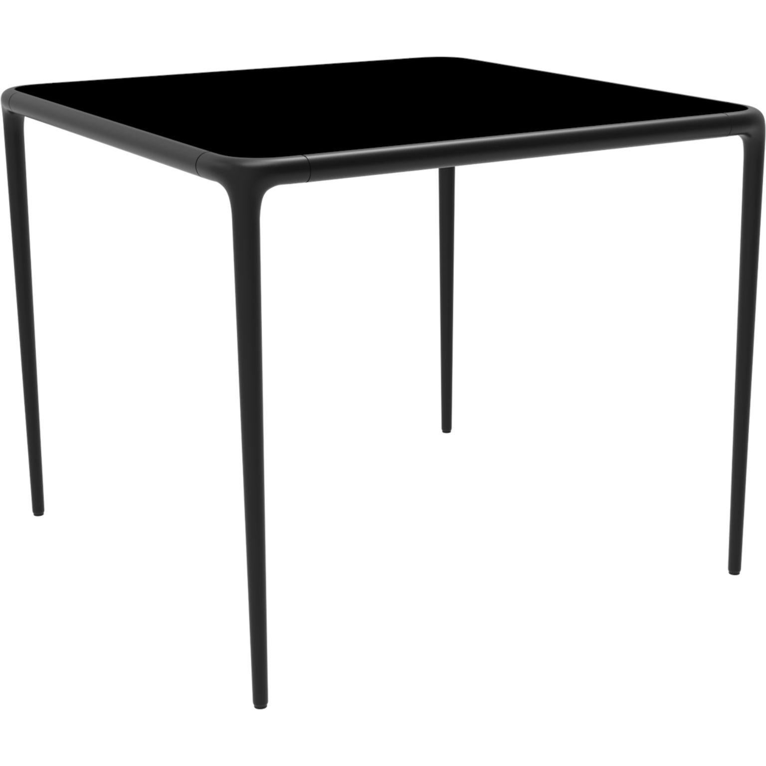 Xaloc black glass top table 90 by Mowee.
Dimensions: D90 x W90 x H74 cm.
Material: Aluminum, tinted tempered glass top.
Also available in different aluminum colors and finishes (HPL Black Edge or Neolith). 

 Xaloc synthesizes the lines of