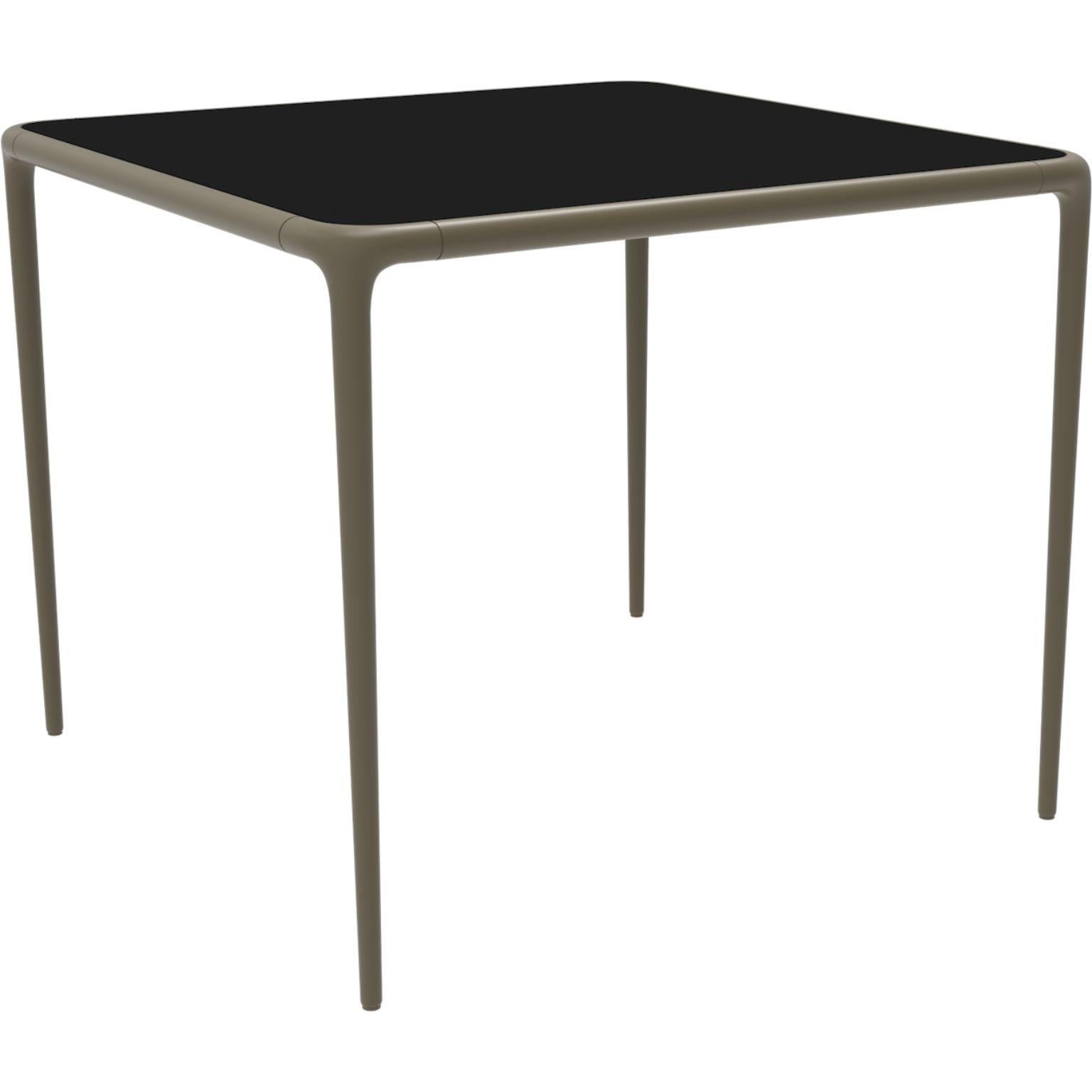 Xaloc bronze glass top table 90 by Mowee.
Dimensions: D90 x W90 x H74 cm.
Material: Aluminum, tinted tempered glass top.
Also available in different aluminum colors and finishes (HPL Black Edge or Neolith). 

Xaloc synthesizes the lines of