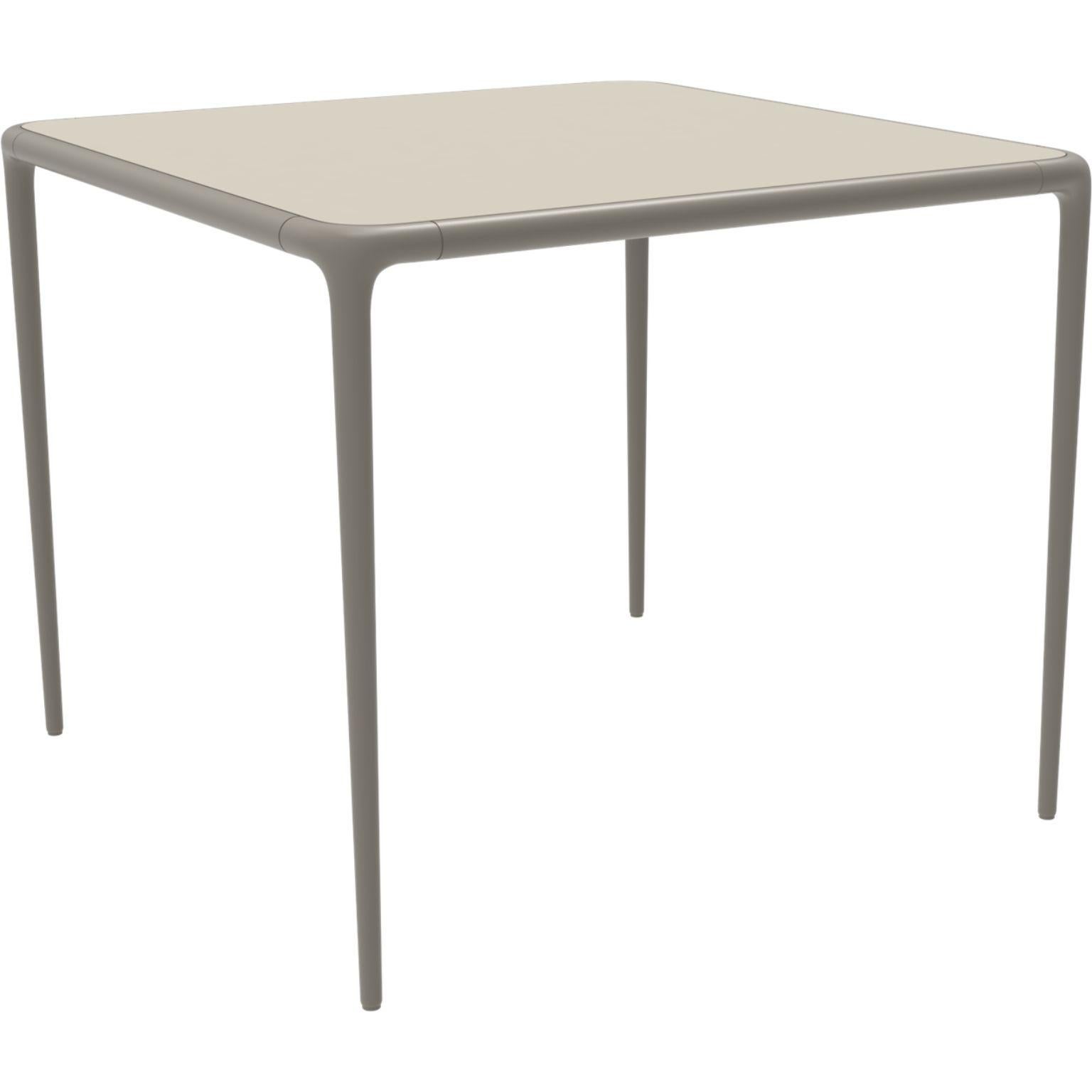 Xaloc cream glass top table 90 by MOWEE
Dimensions: D90 x W90 x H74 cm
Material: Aluminum, tinted tempered glass top.
Also available in different aluminum colors and finishes (HPL Black Edge or Neolith). 

 Xaloc synthesizes the lines of