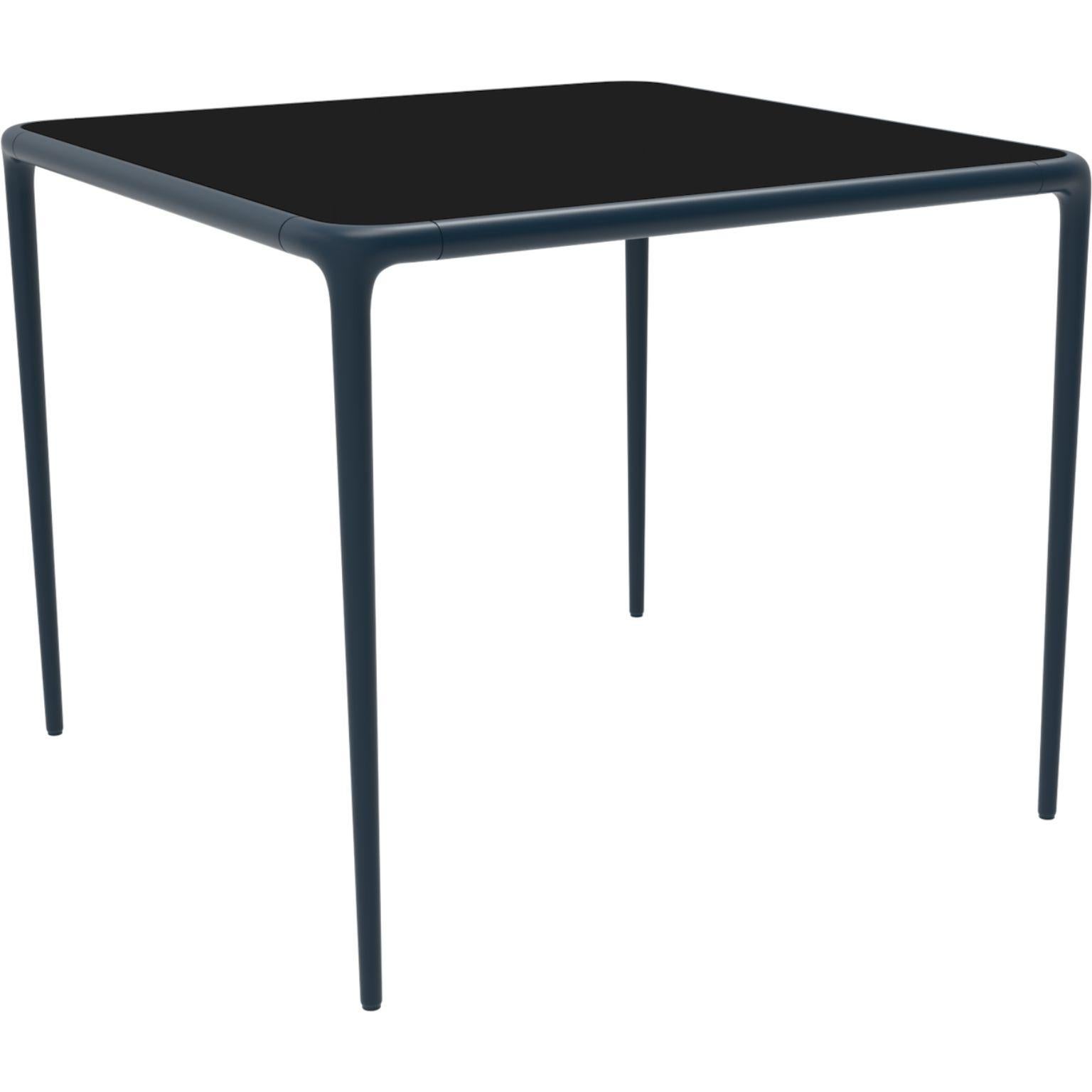 Xaloc Navy glass top table 90 by Mowee
Dimensions: D 90 x W 90 x H 74 cm
Material: Aluminum, tinted tempered glass top.
Also available in different aluminum colors and finishes (HPL Black Edge or Neolith).

 Xaloc synthesizes the lines of
