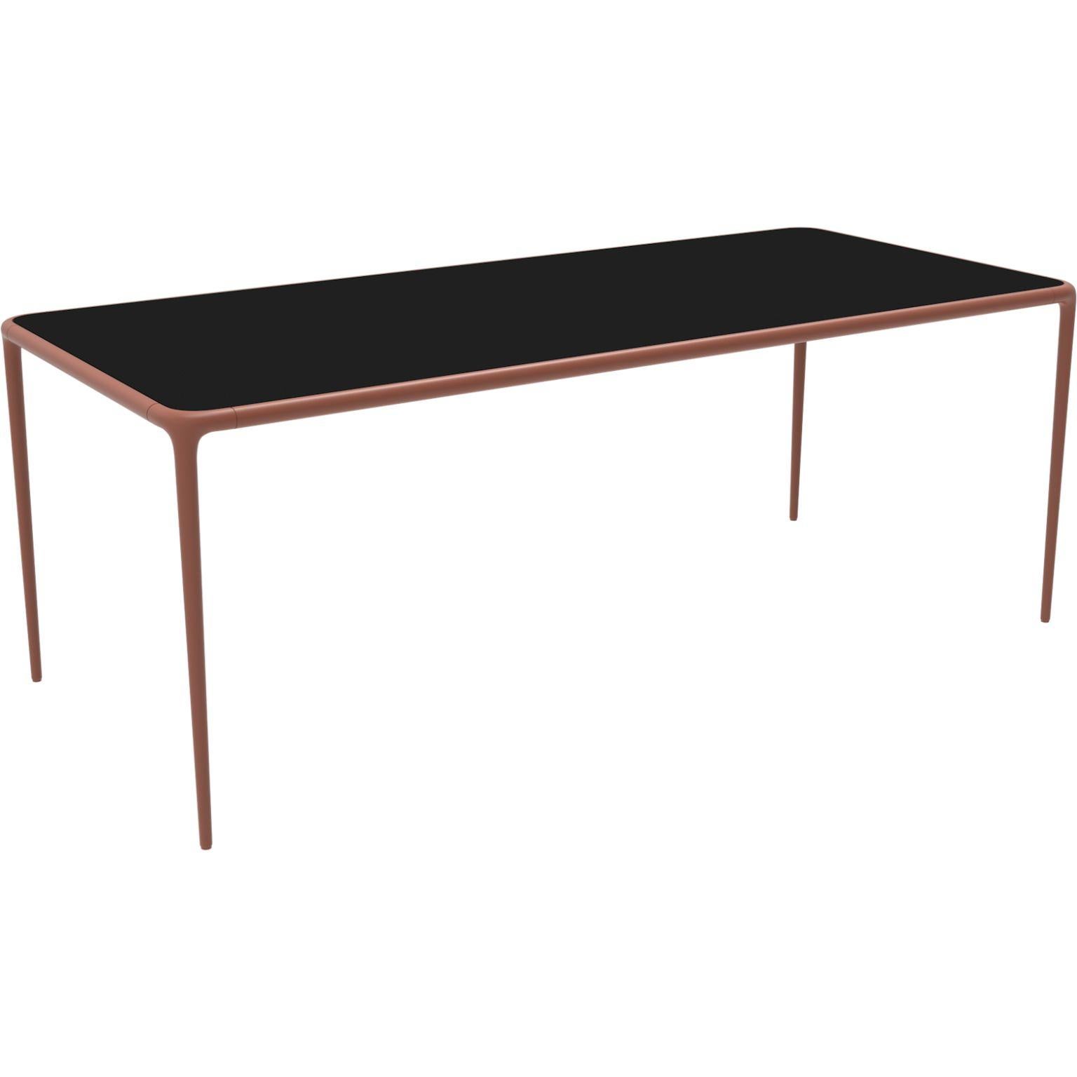 Xaloc salmon glass top 200 table by MOWEE
Dimensions: D200 x W90 x H74 cm
Material: Aluminium, tinted tempered glass top.
Also available in different aluminum colors and finishes (HPL Black Edge or Neolith). 

Xaloc synthesizes the lines of