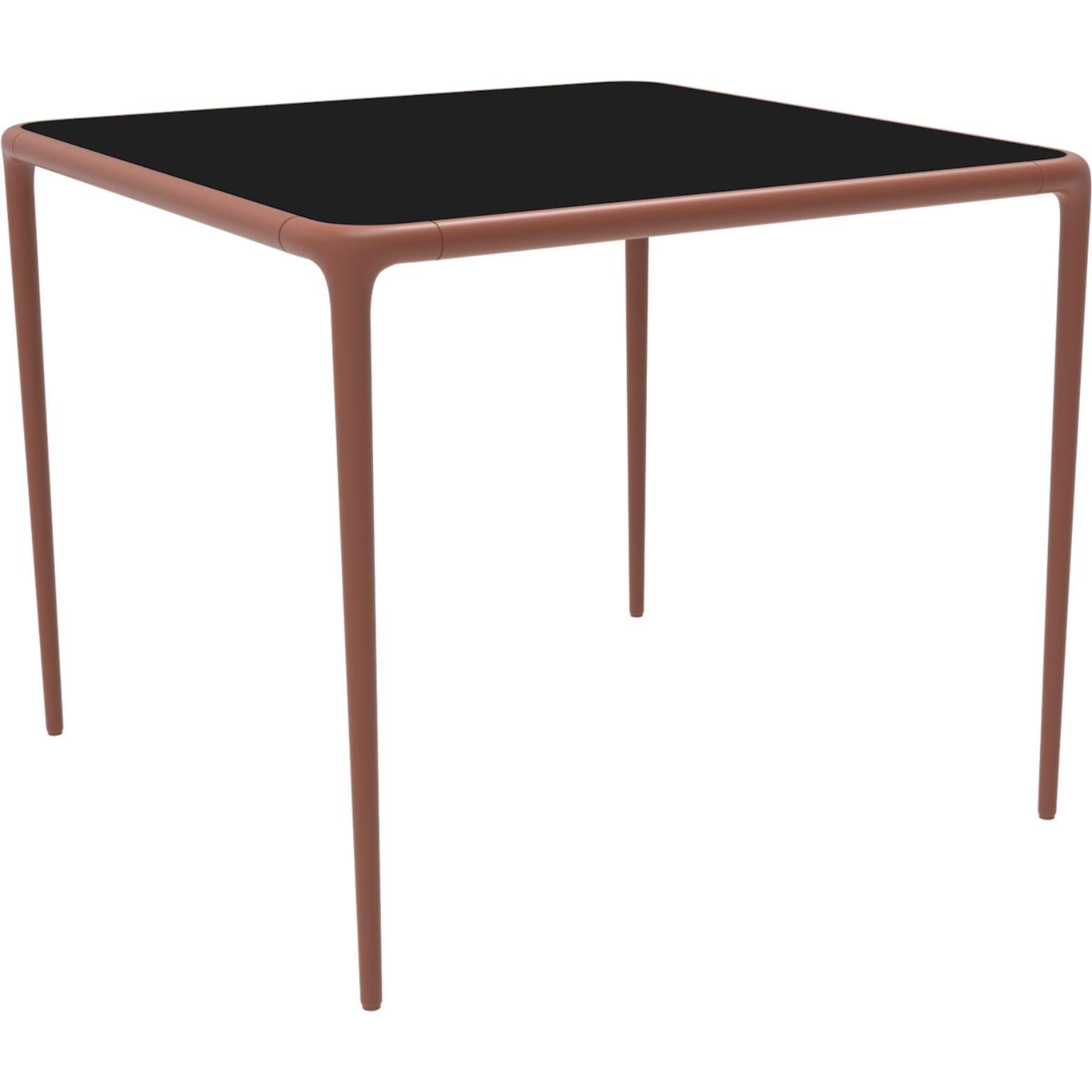 Xaloc Salmon glass top table 90 by Mowee.
Dimensions: D90 x W90 x H74 cm.
Material: Aluminum, tinted tempered glass top.
Also available in different aluminum colors and finishes (HPL Black Edge or Neolith). 

 Xaloc synthesizes the lines of