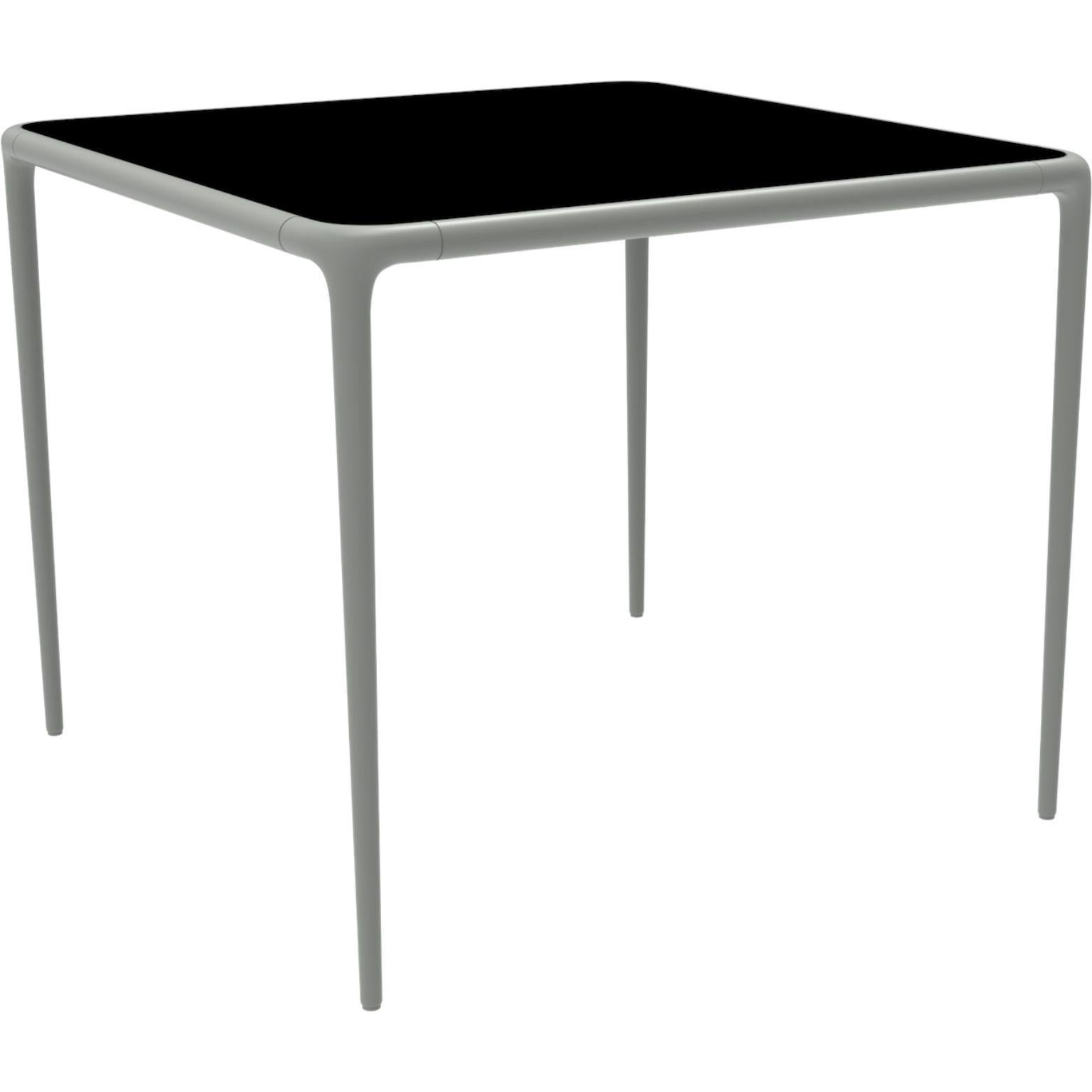 Xaloc silver glass top table 90 by Mowee.
Dimensions: D90 x W90 x H74 cm.
Material: Aluminum, tinted tempered glass top.
Also available in different aluminum colors and finishes (HPL Black Edge or Neolith). 

 Xaloc synthesizes the lines of