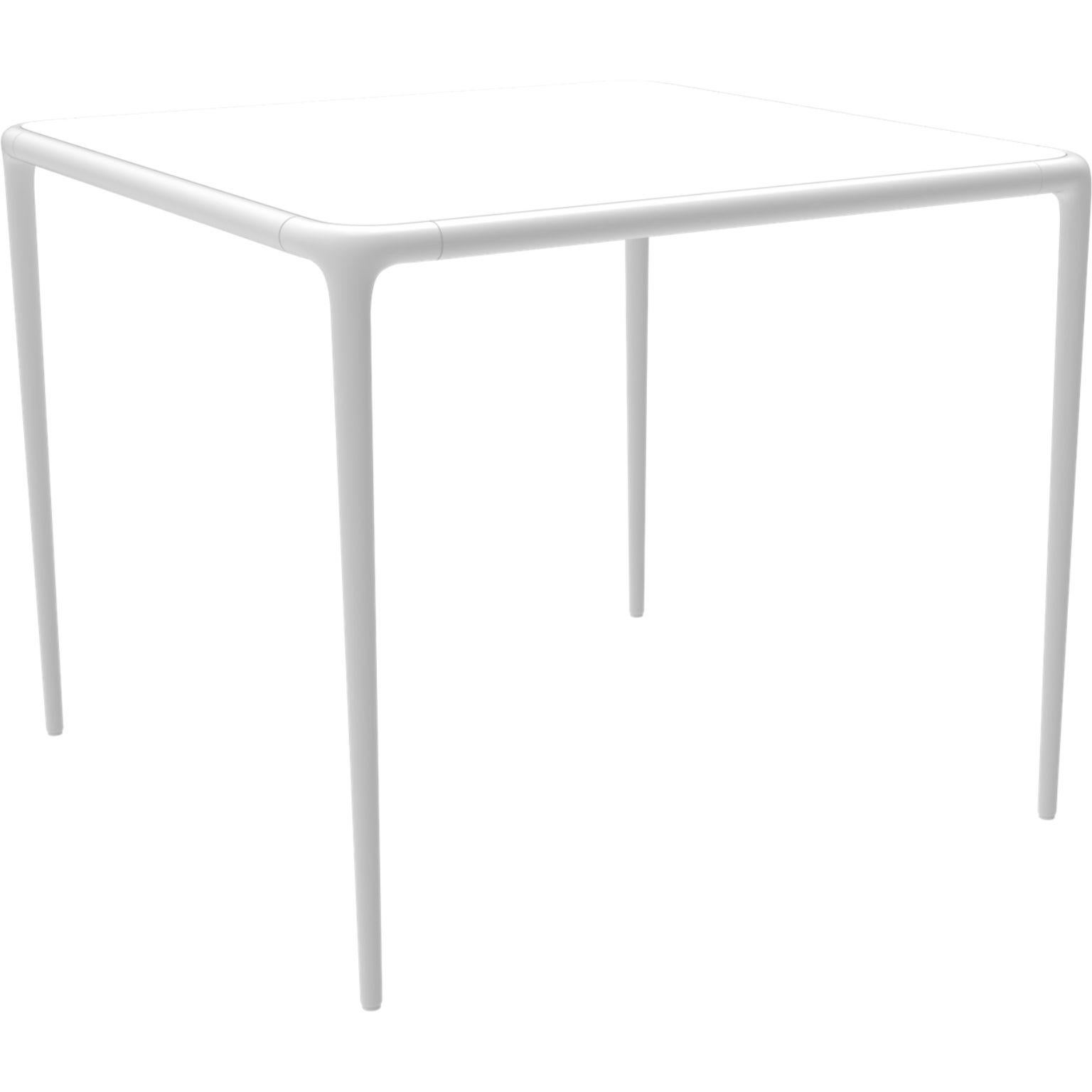 Xaloc white glass top table 90 by MOWEE
Dimensions: D90 x W90 x H74 cm
Material: Aluminum, tinted tempered glass top.
Also available in different aluminum colors and finishes (HPL Black Edge or Neolith). 

 Xaloc synthesizes the lines of