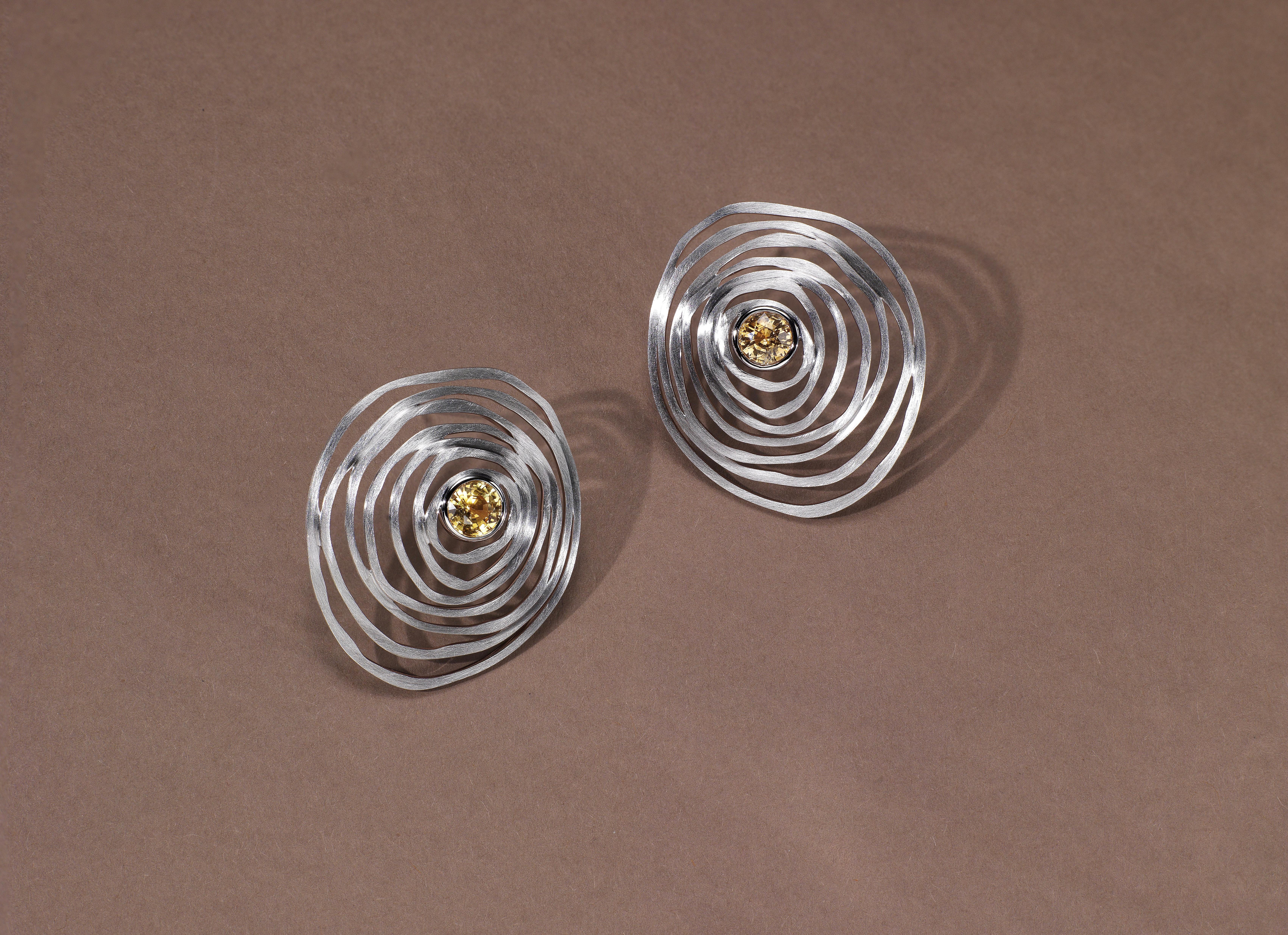 The central colored gemstone creates a ripple effect with seven layers, each gently curved for an elegant wearing experience. The ripple layers are three-dimensional, with each one stacked upon the next, rather than lying flat. As you move, the