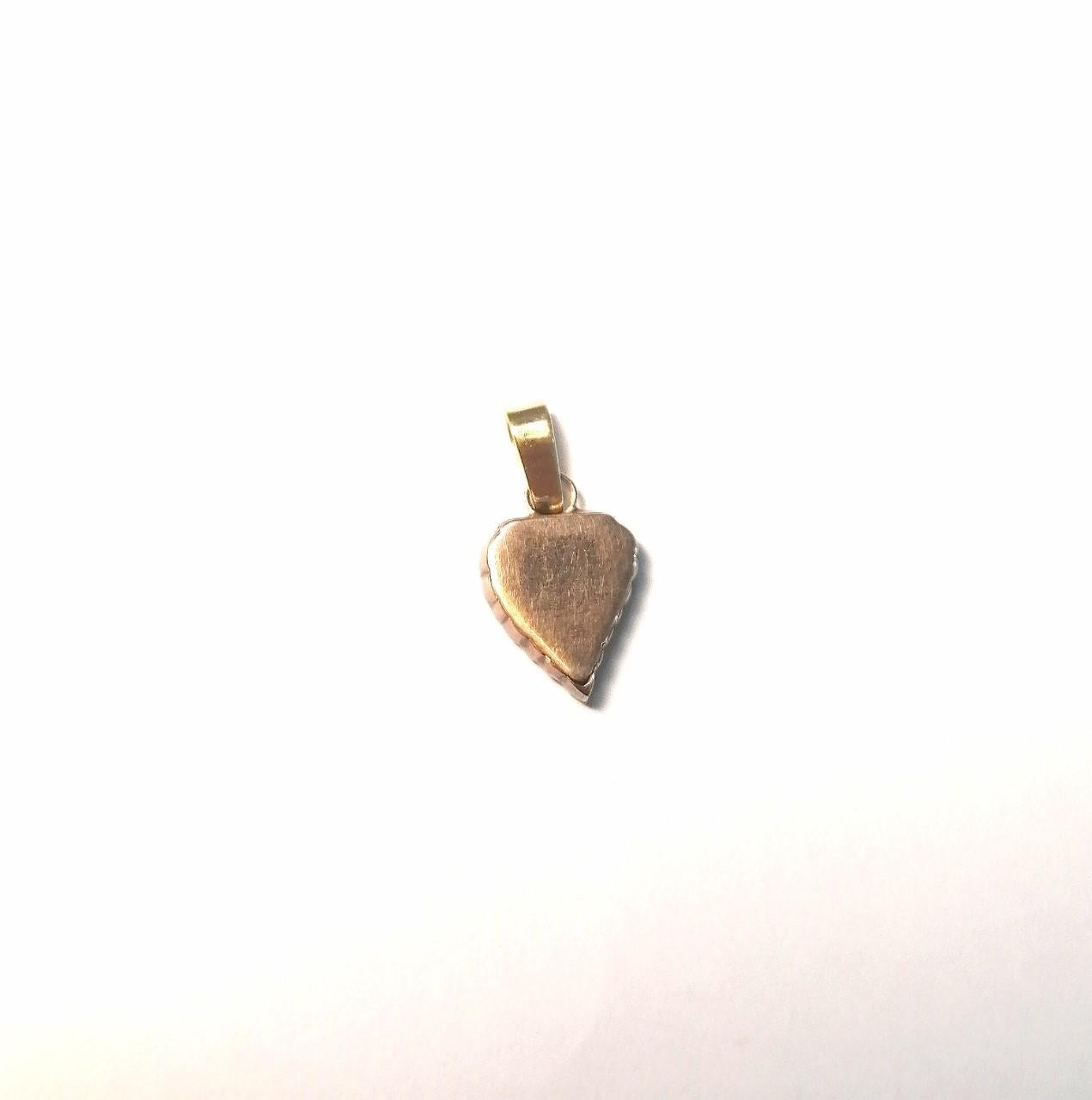 14k gold heart shaped pendant with approximately 0.40 carat of old cut diamonds. The handle is later made in 18 k gold  It has a total length of 24 millimeters with handle. The inside is hollow to keep a memory.