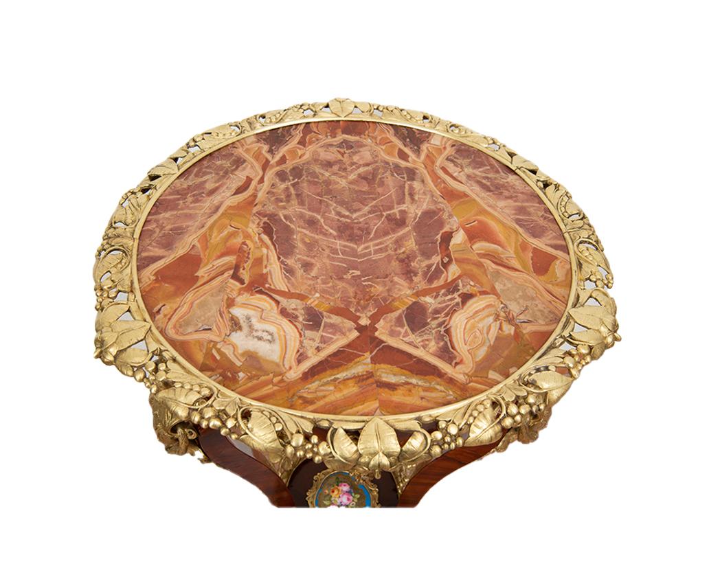 Table basse Napoléon III en bois exotique français avec plateau en marbre de Jaspe de Sicile. Le plateau en marbre est entouré d'éléments en bronze doré avec un motif de feuilles.
Le bandeau mixtiligne sous le comptoir est enrichi par la présence