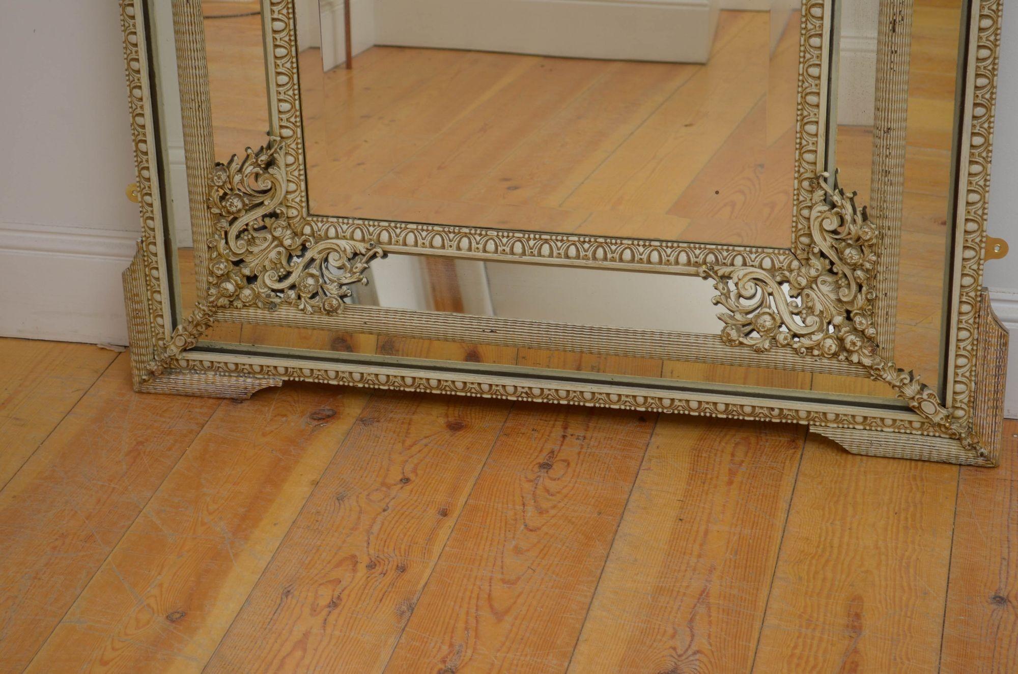 Sn5389 A 19th century French, wall mirror with double cushioning, having original glass with foxing and minor imperfections in egg and dart carved frame with floral metal mounts to the corners and ripple effect throughout, all flanked by shaped